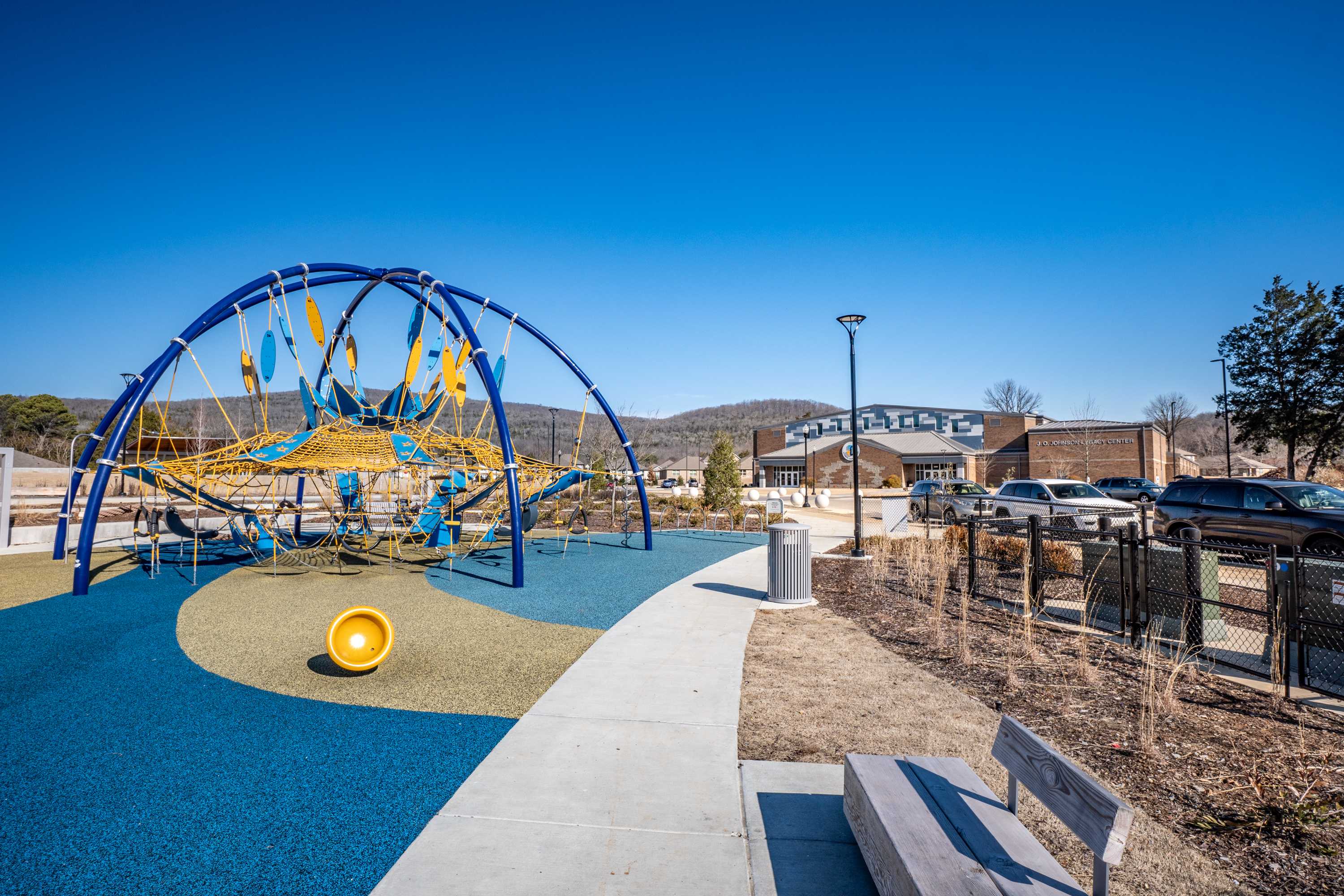 Vibrant playground at Jaguar Hills in Huntsville Alabama with blue climbing arches yellow dome and rubber surfacing