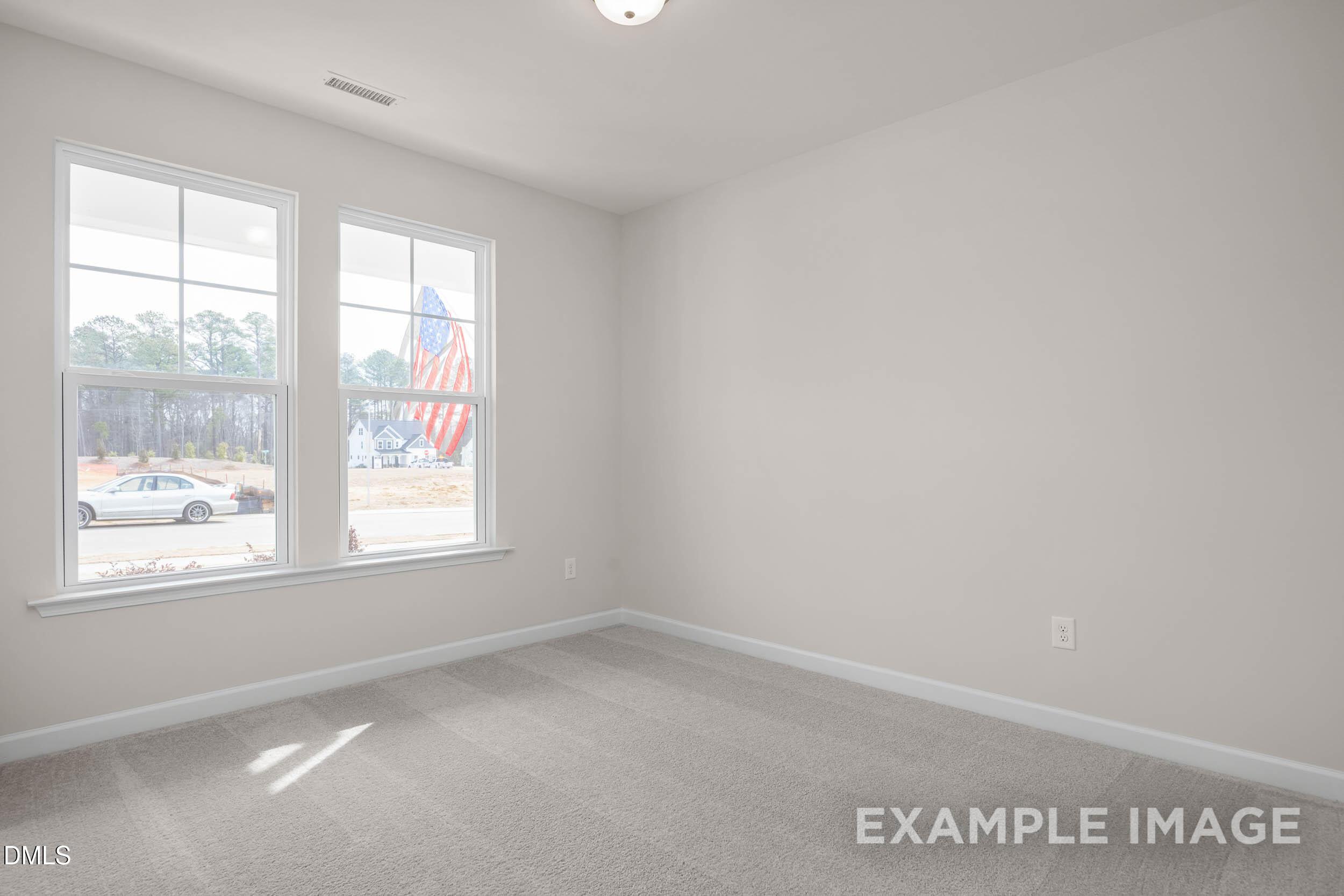 Bright, neutral bedroom with carpet and large windows in The Franklin C floor plan at Retreat at North Main, Lillington.