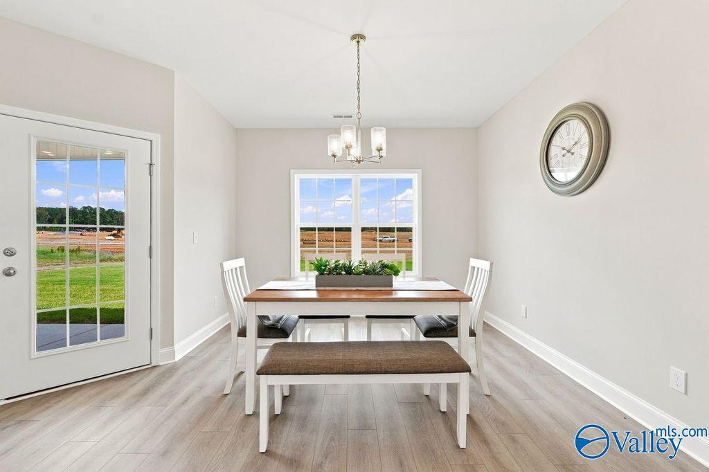 Bright dining area with wood-look flooring, white table, bench seating, and chandelier in Davidson Homes' The Harrison, Hartselle, AL