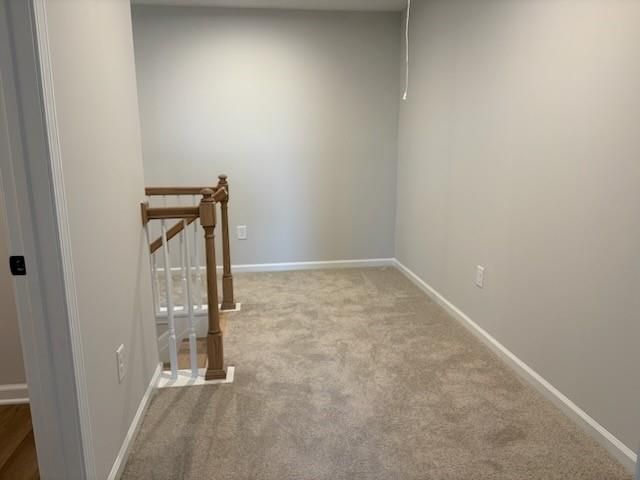 Spacious upstairs hallway with wooden balustrade, beige carpet, and light gray walls in Davidson Homes Cary A, Winder, GA