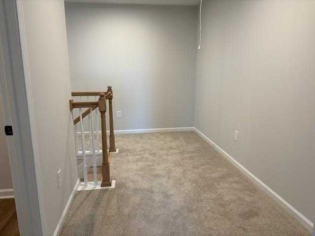 Spacious upstairs hallway with wooden balustrade, beige carpet, and light gray walls in Davidson Homes Cary A, Winder, GA