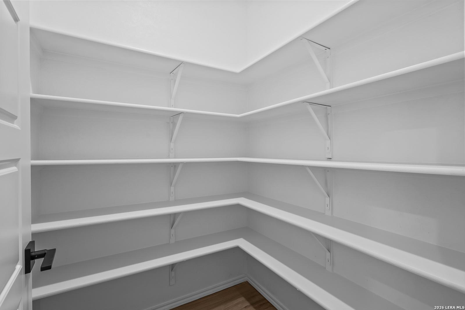 Walk-in closet with wraparound white shelving and black door hardware in Davidson Homes Sequoia C plan, Royal Crest, San Antonio