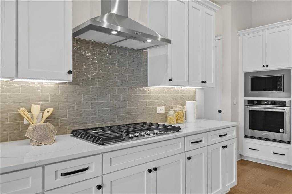Modern white shaker kitchen with gas cooktop, double ovens, gray subway backsplash in Davidson Homes The Seaside B, Woodstock, GA