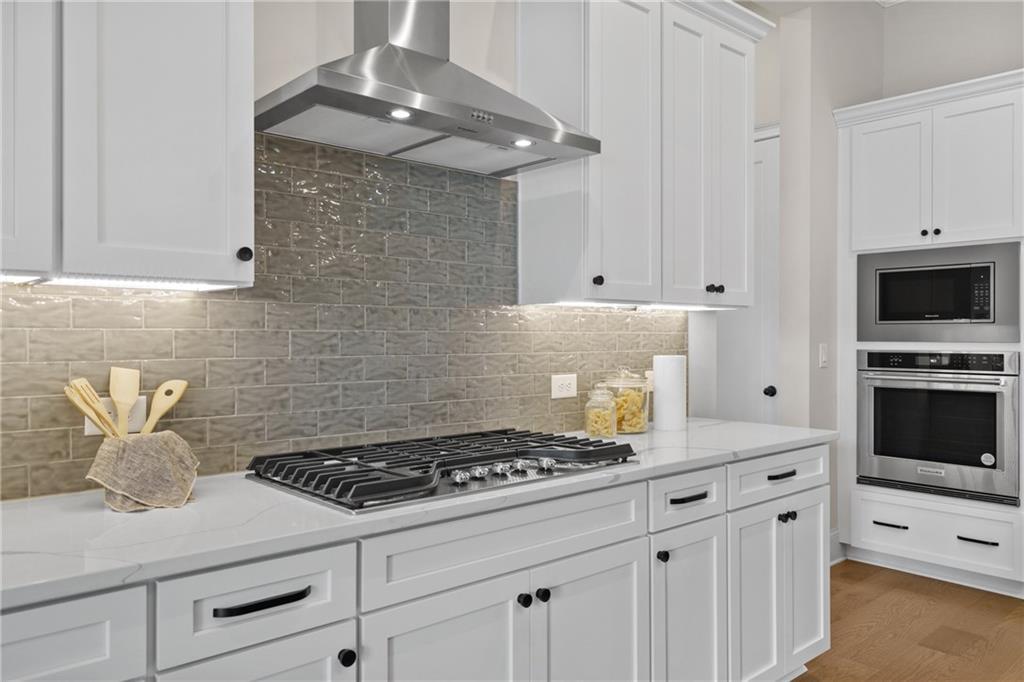 Modern white shaker kitchen with gas cooktop, double ovens, gray subway backsplash in Davidson Homes The Seaside B, Woodstock, GA