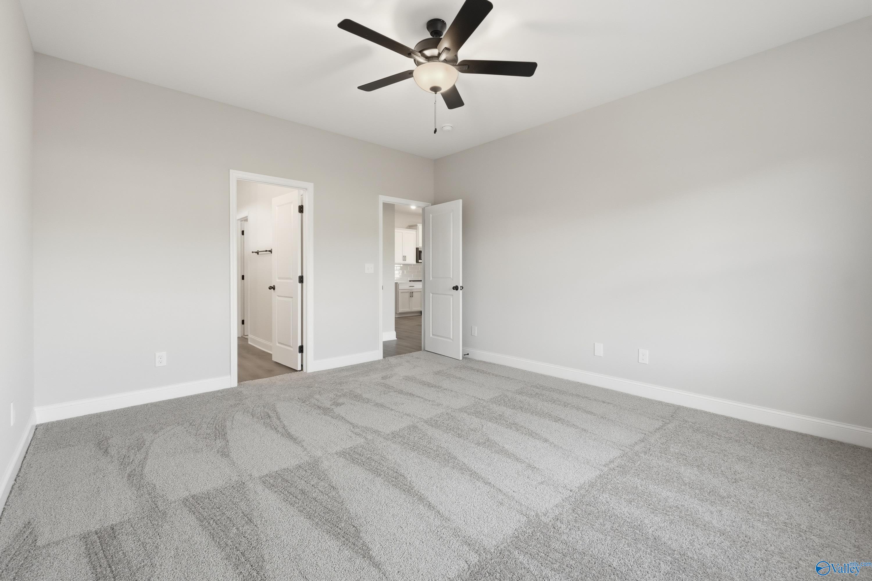 Spacious secondary bedroom with ceiling fan, gray carpet, and adjacent bath in Davidson Homes The Daphne D, Arab, Alabama
