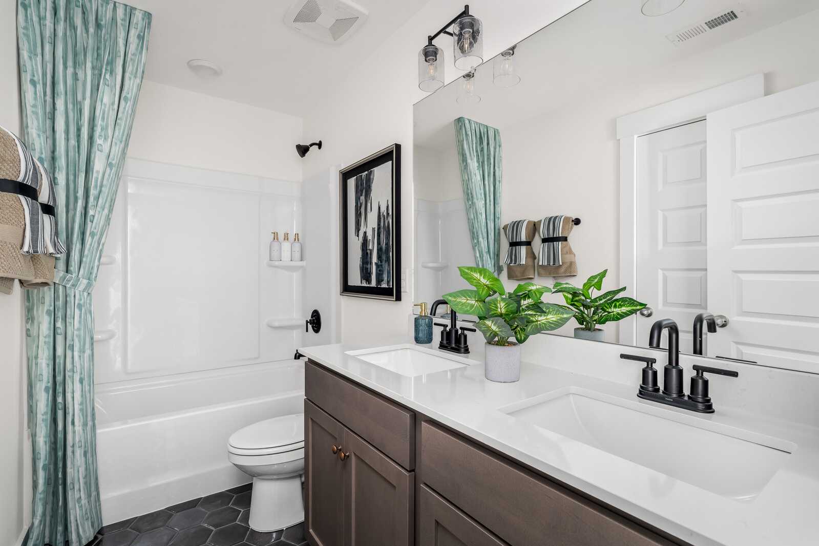 Modern bathroom at Woods Crossing in Gallatin TN with double vanity, freestanding tub, subway tile, and teal shower curtain
