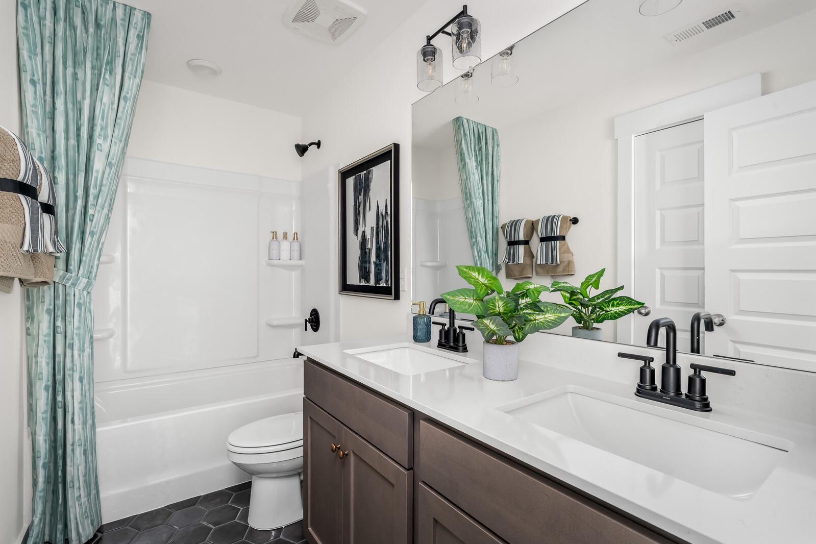 Modern bathroom at Woods Crossing in Gallatin TN with double vanity, freestanding tub, subway tile, and teal shower curtain
