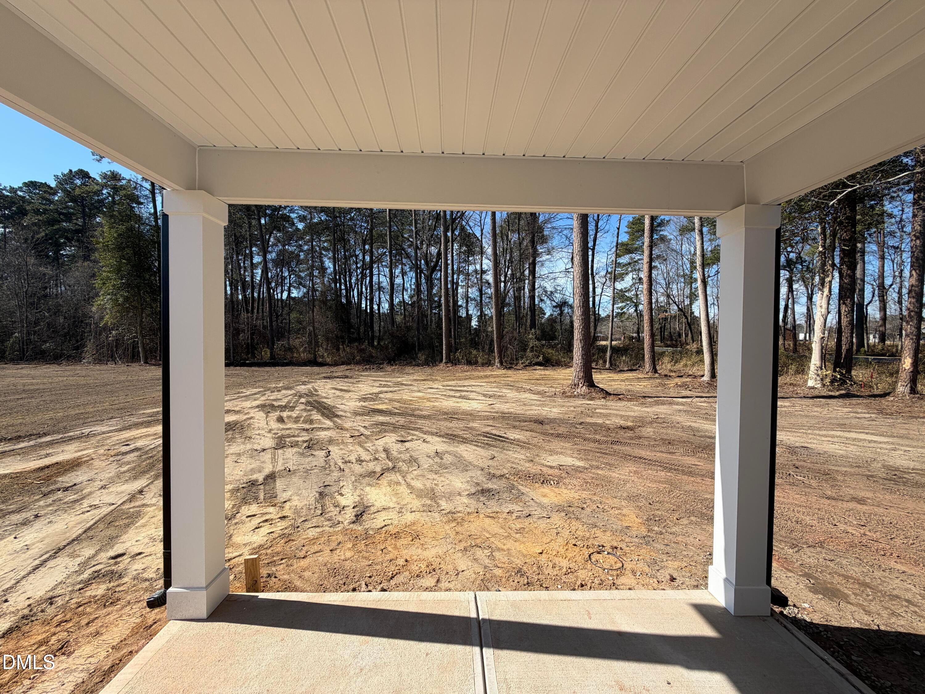 Covered back patio with white columns overlooking sandy backyard and pine trees in Davidson Homes The Carter C, Wellers Knoll, Lillington, NC