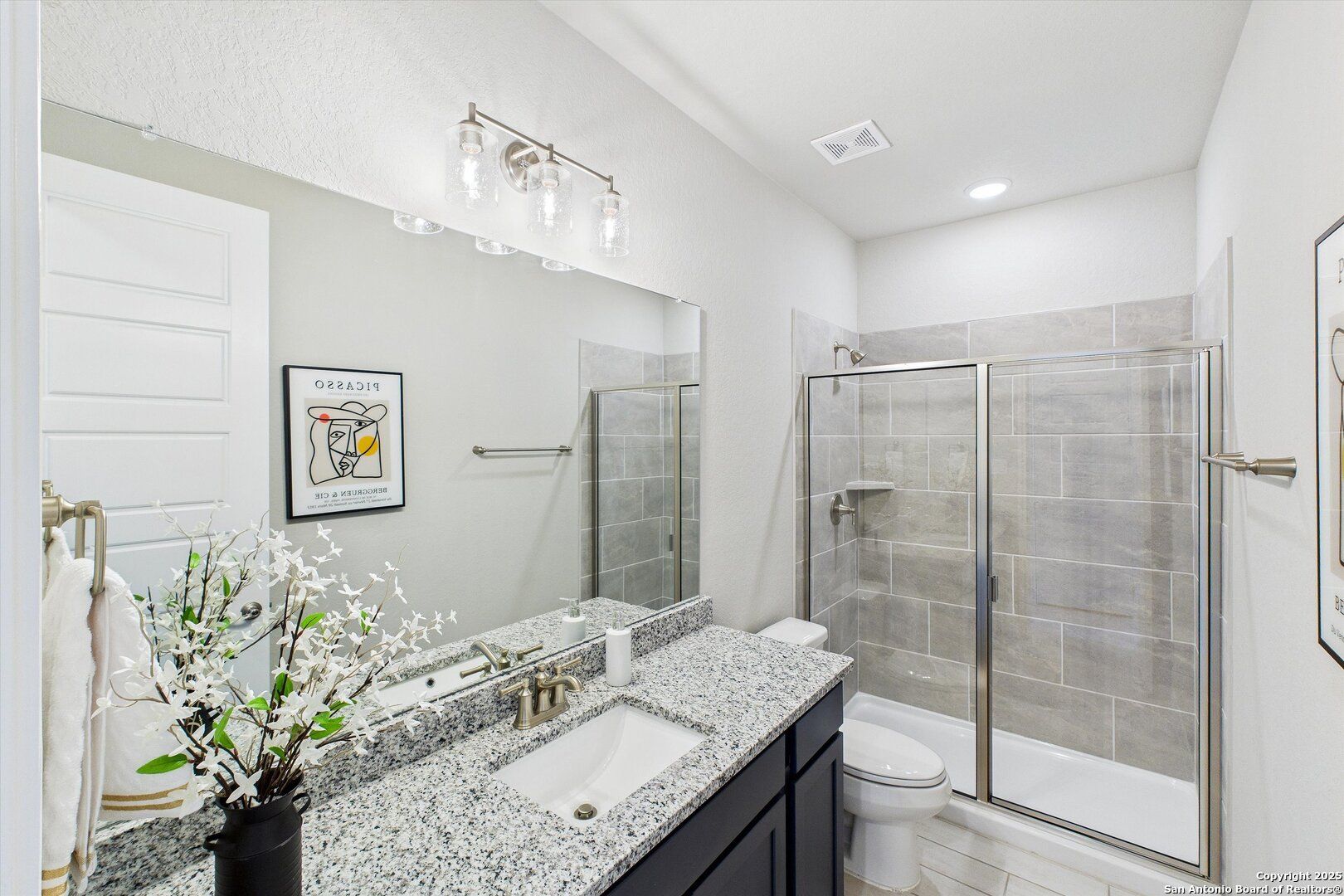 Modern bathroom with granite vanity, glass shower enclosure, and tiled walls in The Jennings H by Davidson Homes, Ladera, San Antonio