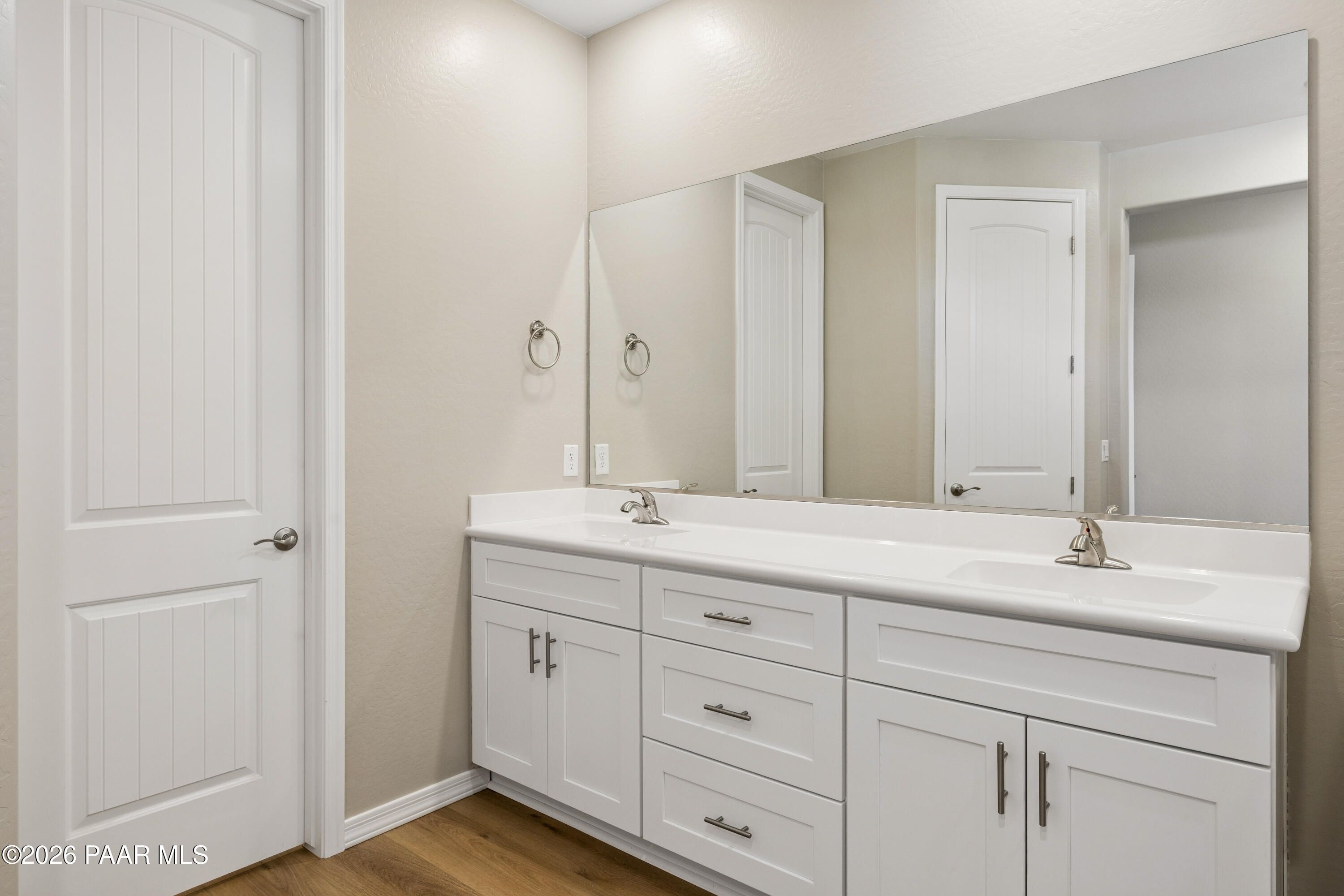 Modern double vanity with white cabinets, large mirror, and beige walls in Davidson Homes The Harmony A, Prescott Valley, AZ