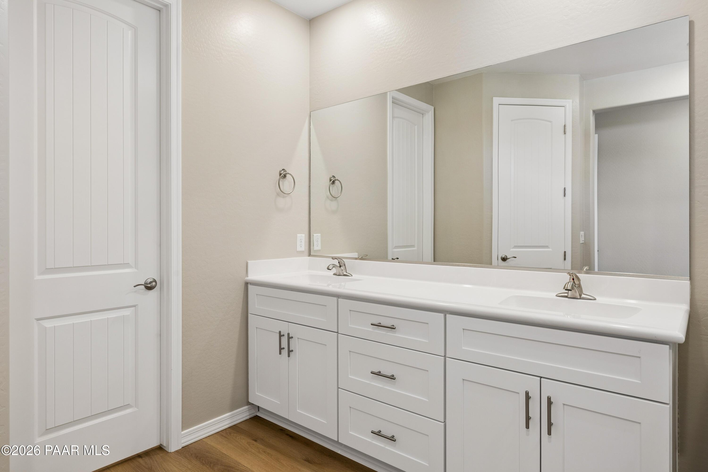 Modern double vanity with white cabinets, large mirror, and beige walls in Davidson Homes The Harmony A, Prescott Valley, AZ