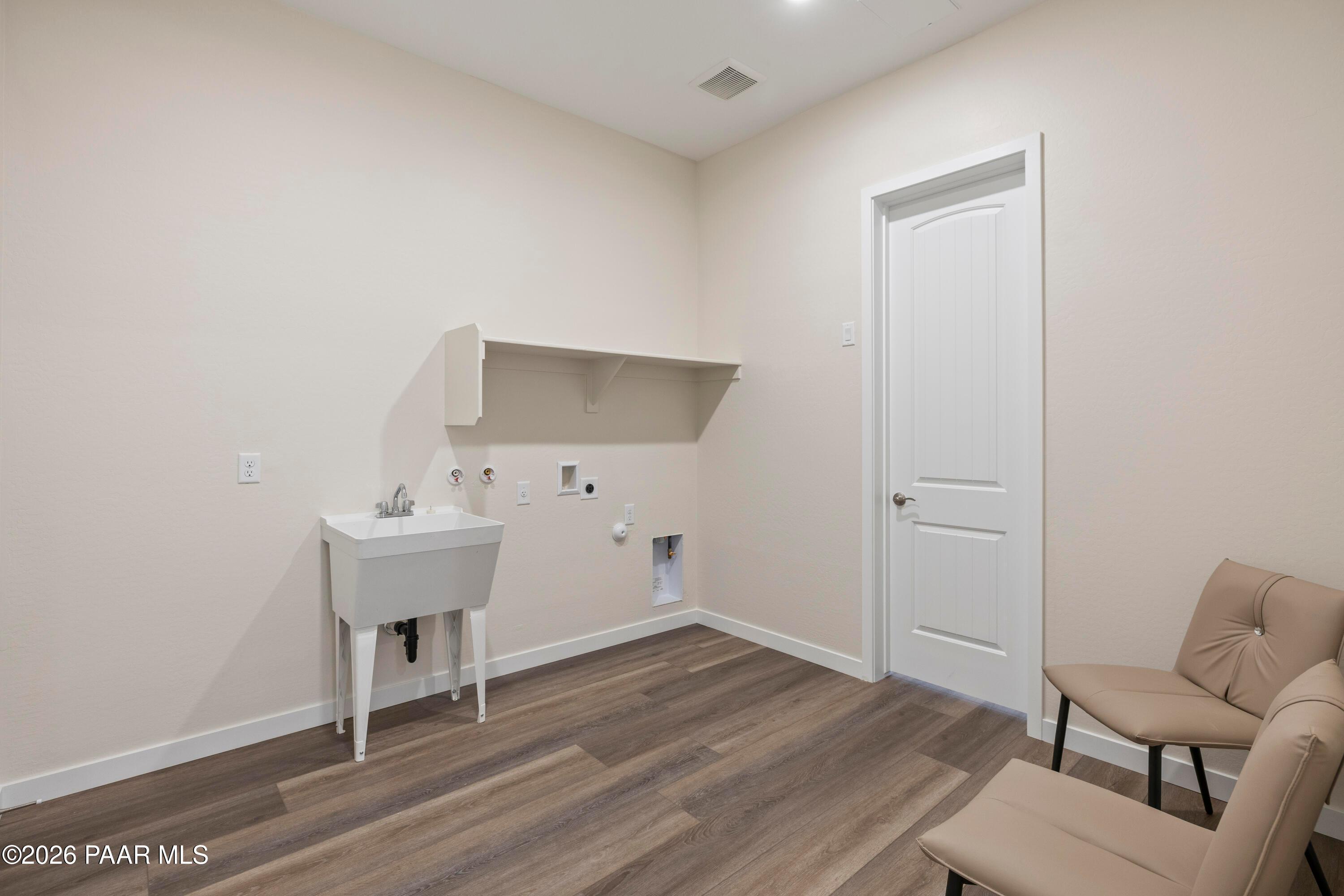 Spacious laundry room with utility sink, storage shelf, and upholstered chairs in Davidson Homes Soleil E, Hidden Hills, Prescott, AZ