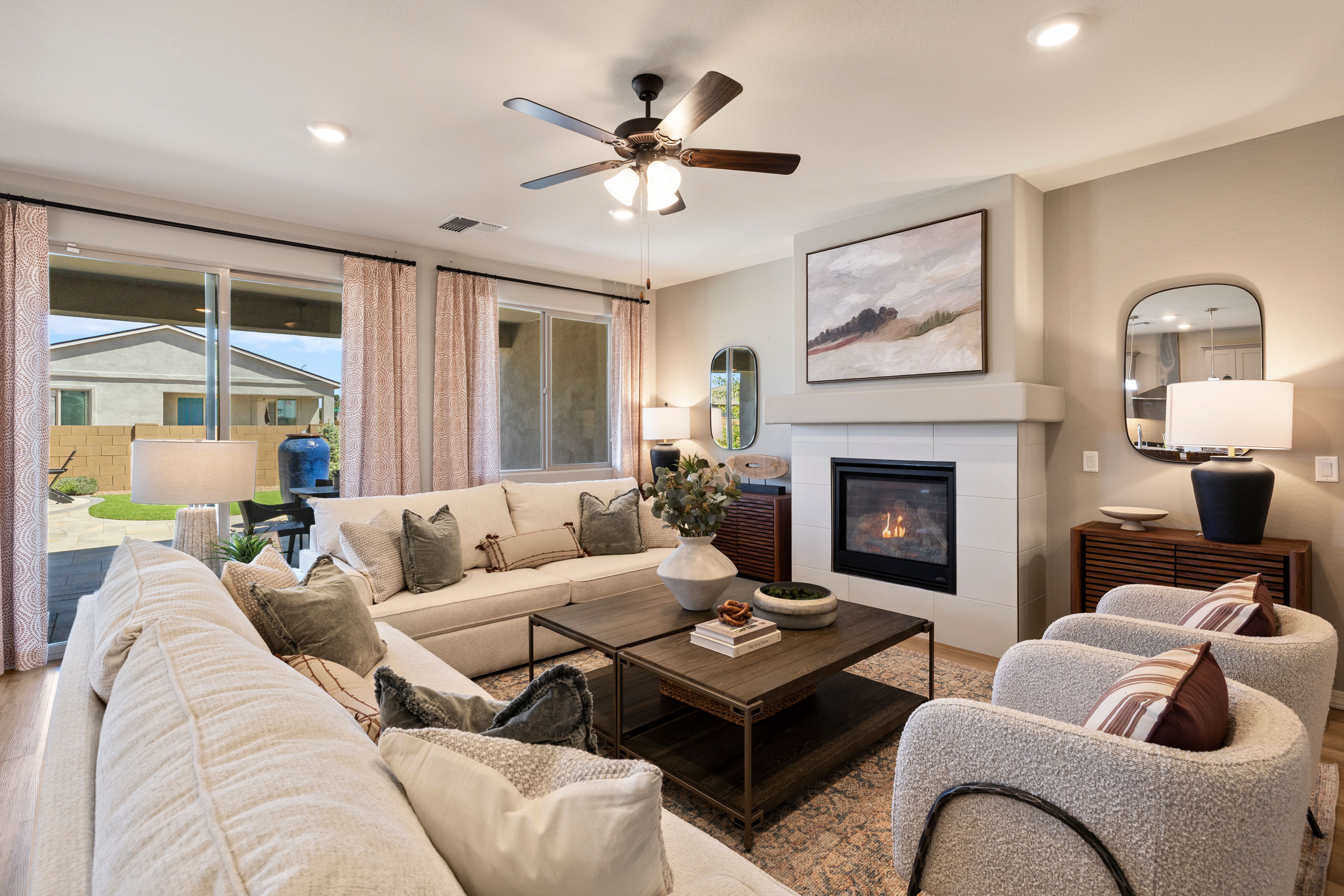 Spacious living room at North Ridge Pronghorn Ranch in Prescott Valley AZ with cream sectional sofa, gas fireplace, and backyard views
