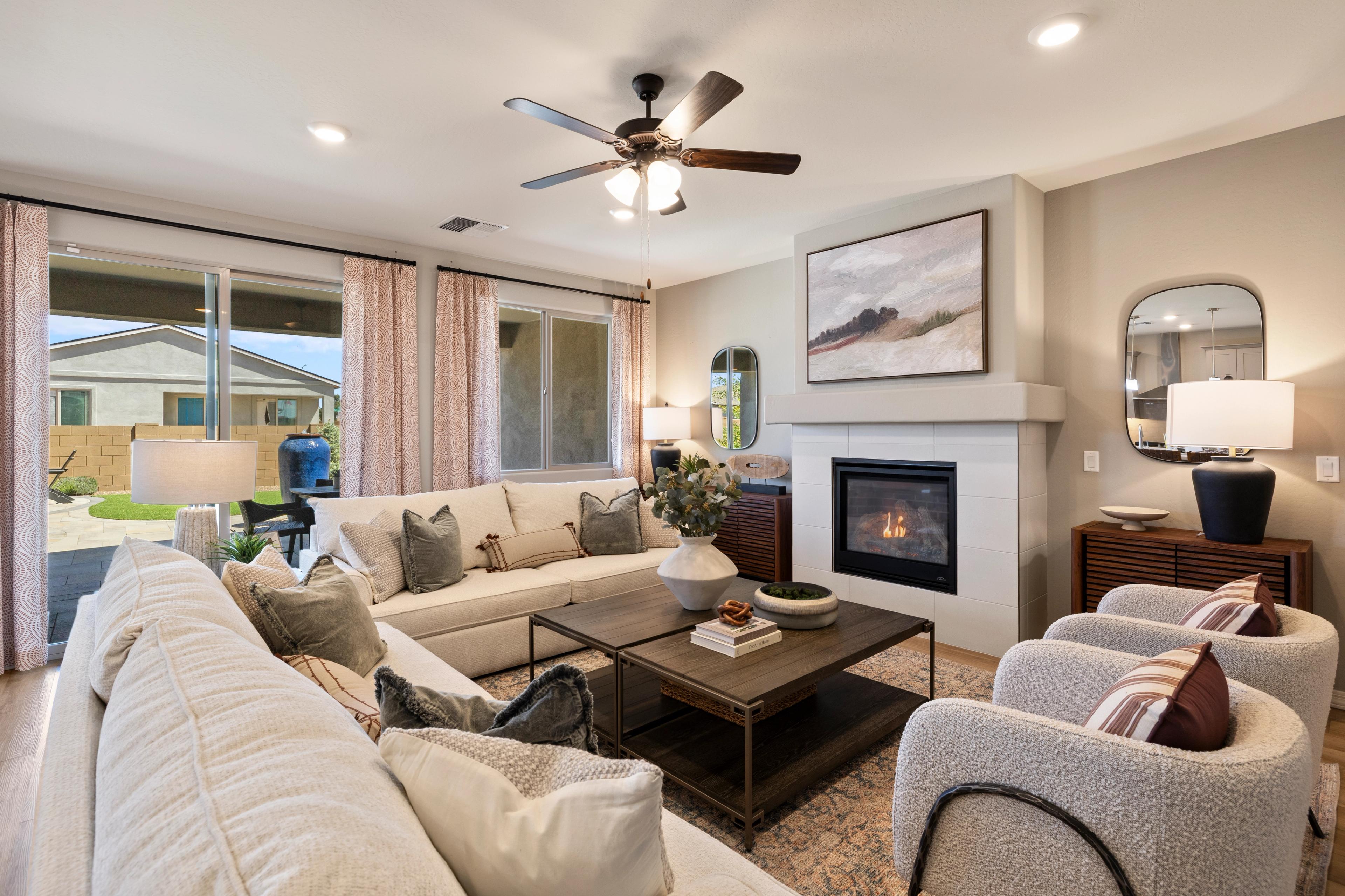 Spacious living room at North Ridge Pronghorn Ranch in Prescott Valley AZ with cream sectional sofa, gas fireplace, and backyard views