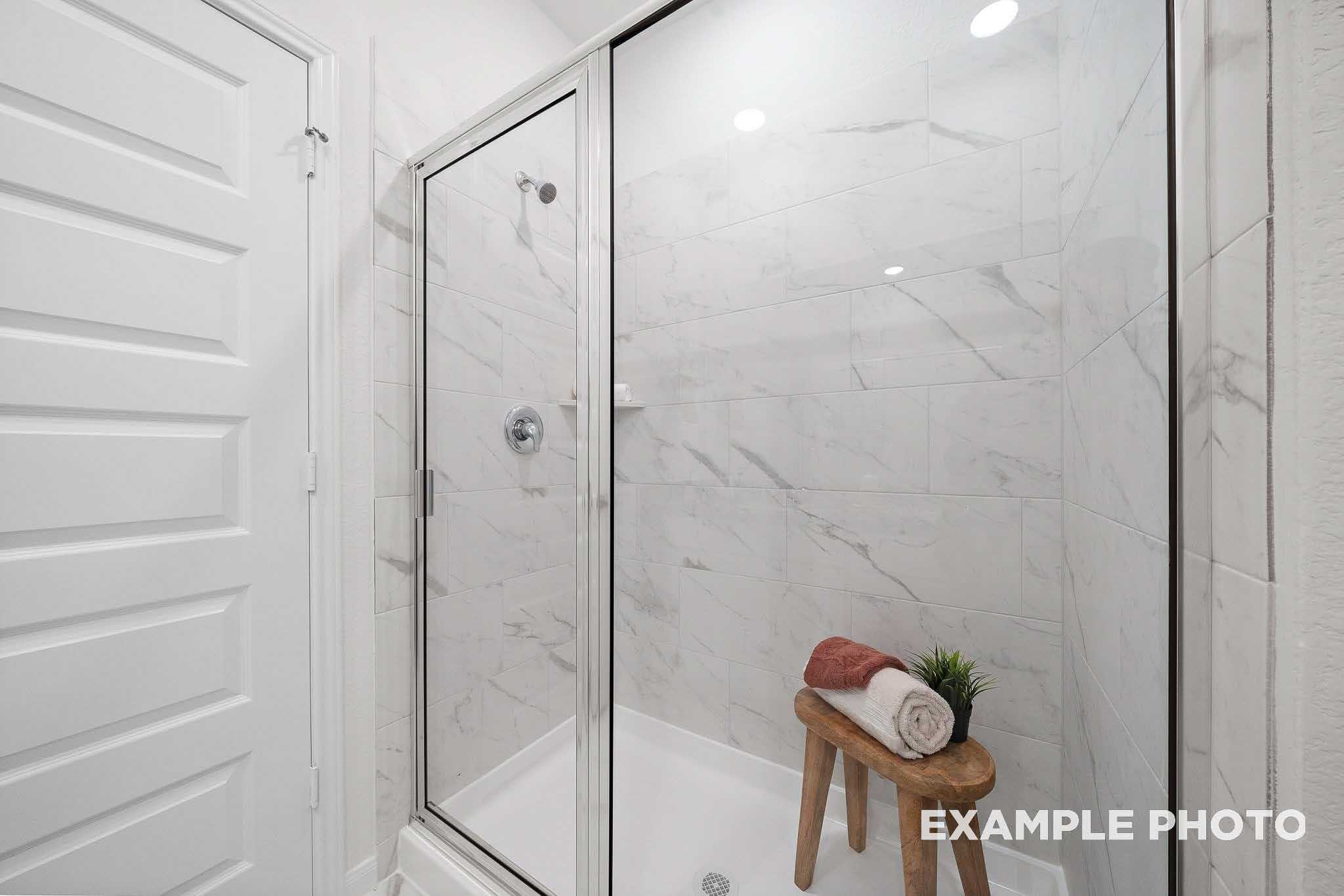 Modern walk-in shower with white subway tiles, chrome fixtures, and towel stool in Davidson Homes The Sabine F, Magnolia, Texas