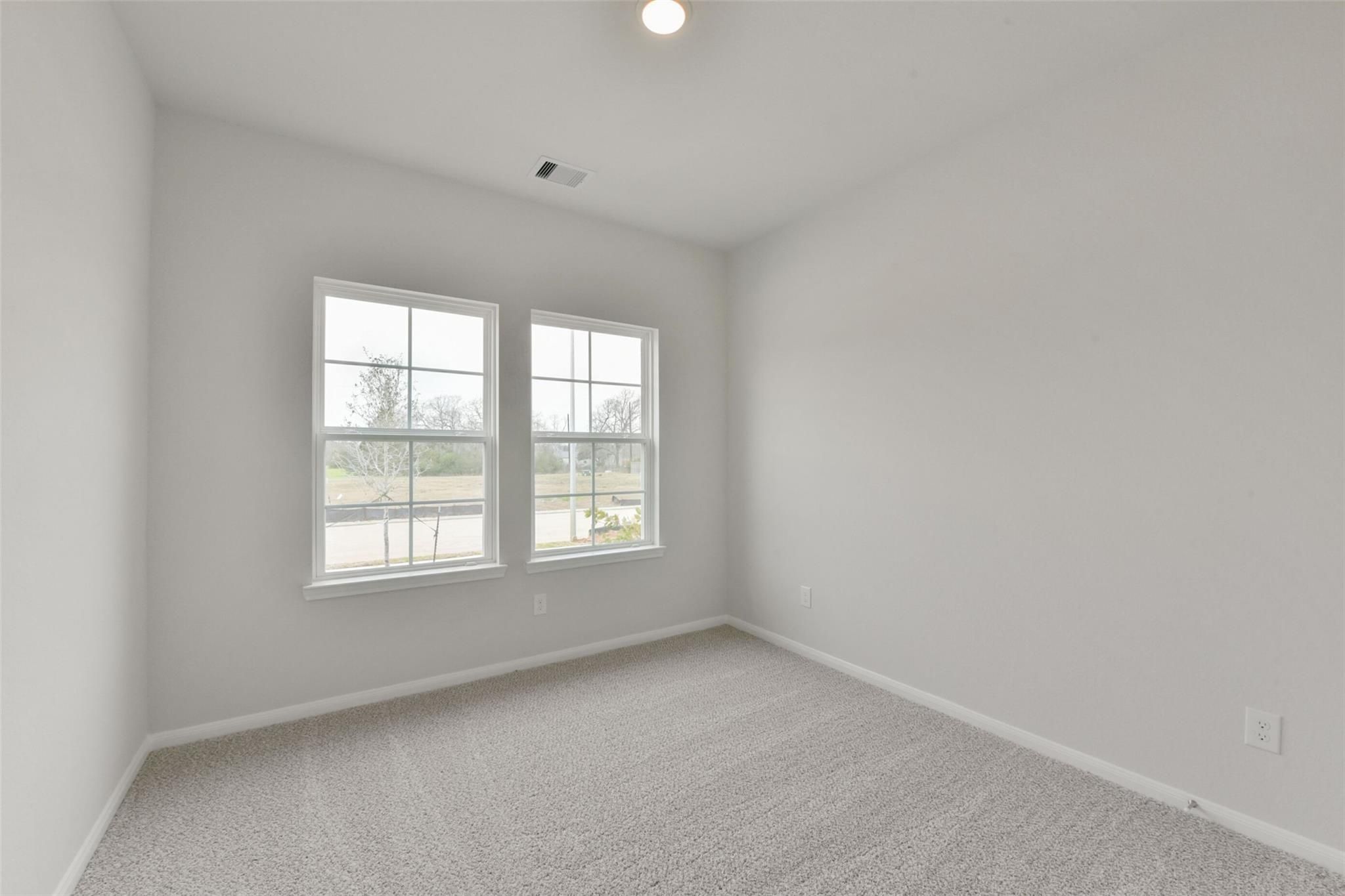 Bright secondary bedroom with large windows, gray walls, and carpeted floor in Davidson Homes The Laguna B, Magnolia, Texas