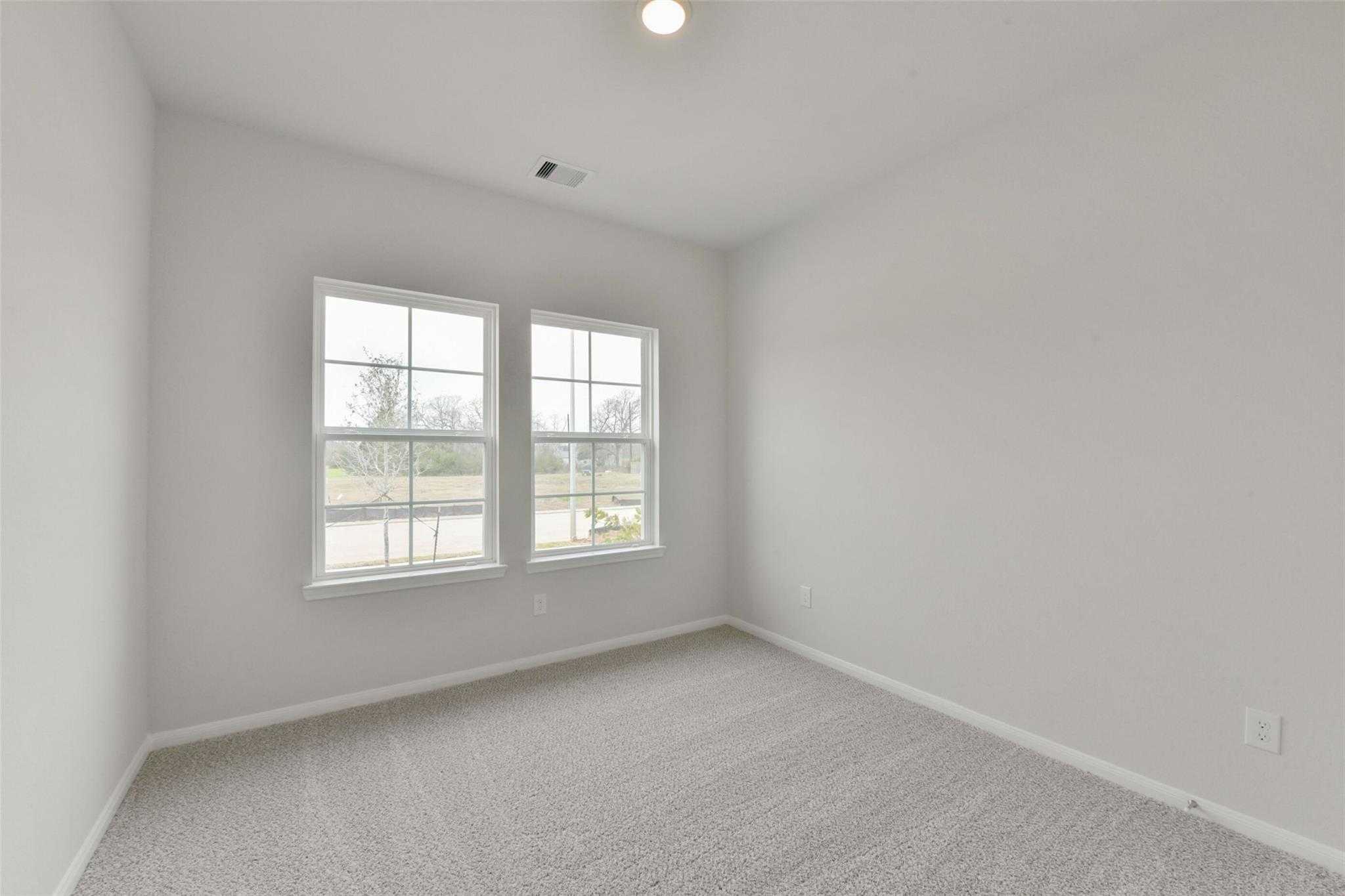 Bright secondary bedroom with large windows, gray walls, and carpeted floor in Davidson Homes The Laguna B, Magnolia, Texas