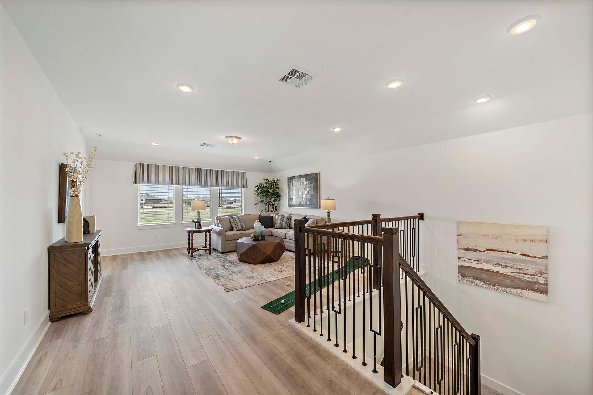 Open-concept living area with staircase in Sierra Vista Rosharon TX by Davidson Homes featuring light wood floors modern decor and large windows