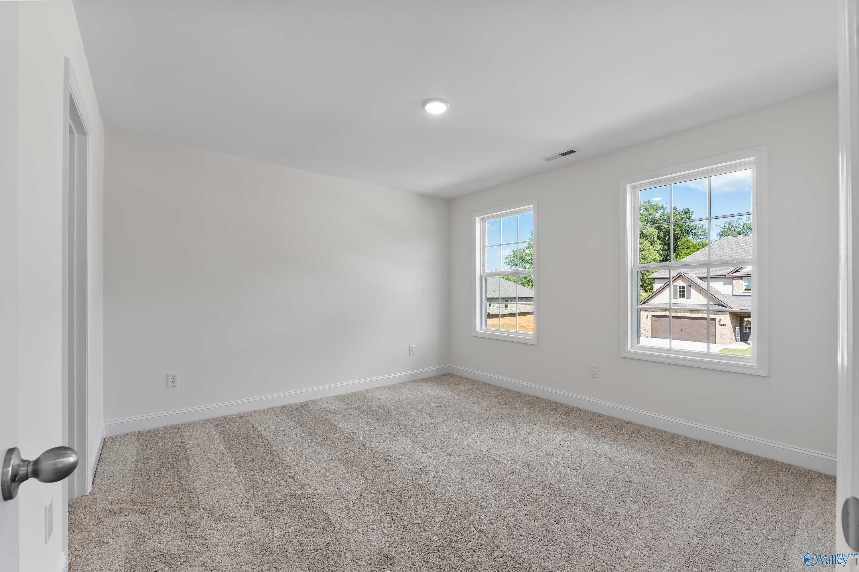 Spacious secondary bedroom with beige carpet, white walls, and large windows overlooking greenery in Davidson Homes The Shelby A, New Market, AL