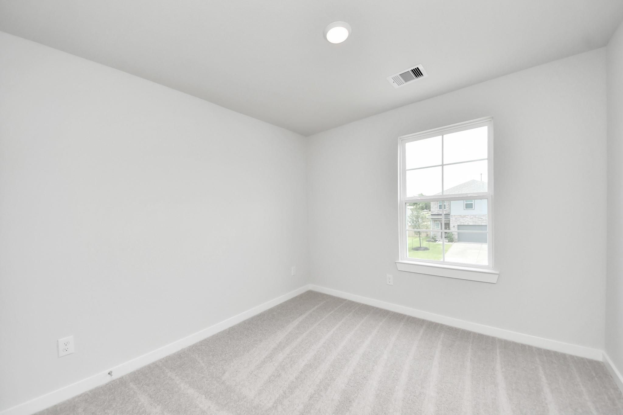 Bright secondary bedroom with plush carpeting in The Blanco E floor plan at Caney Creek Place, Conroe, Texas.