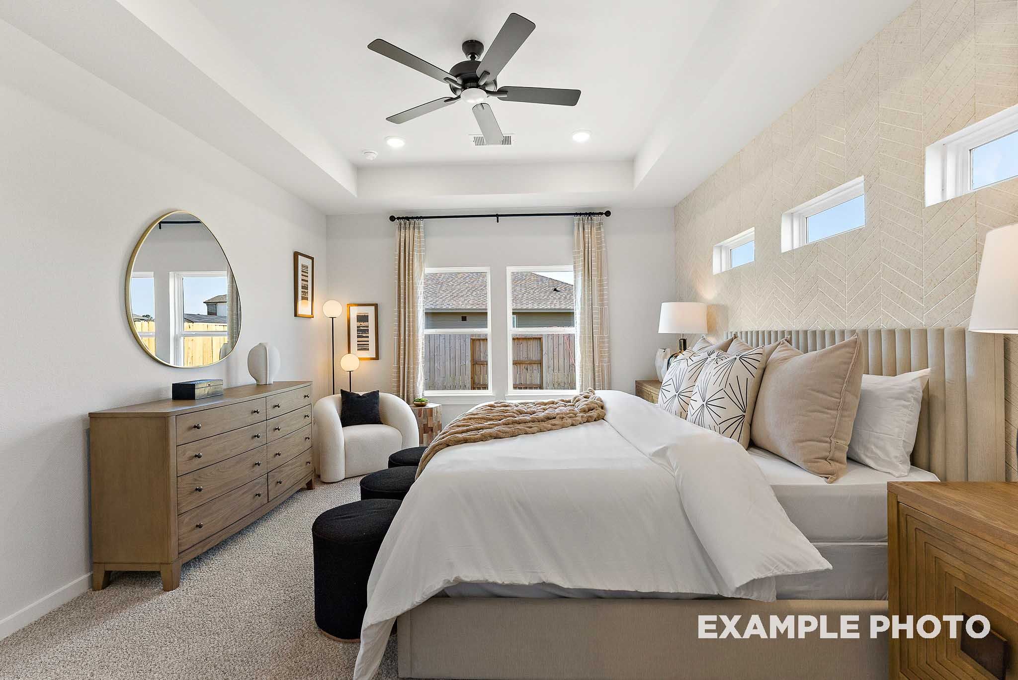 Primary bedroom with tray ceiling and textured accent wall in The Everett E floor plan at Sundance Cove, Crosby, Texas.