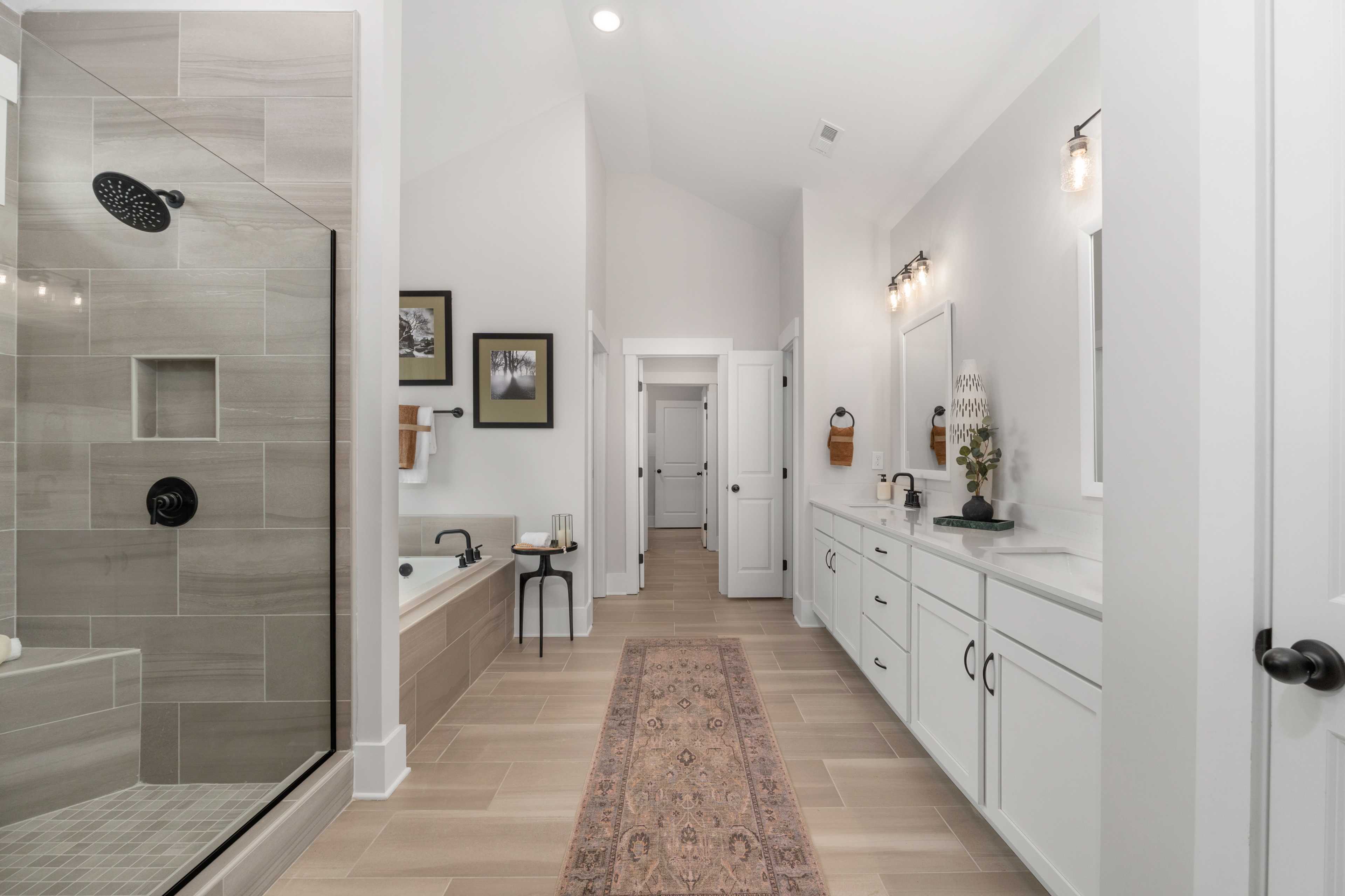 Spacious master bathroom at Briercreek in Meridianville Alabama featuring walk-in glass shower freestanding tub double vanity and hardwood floors