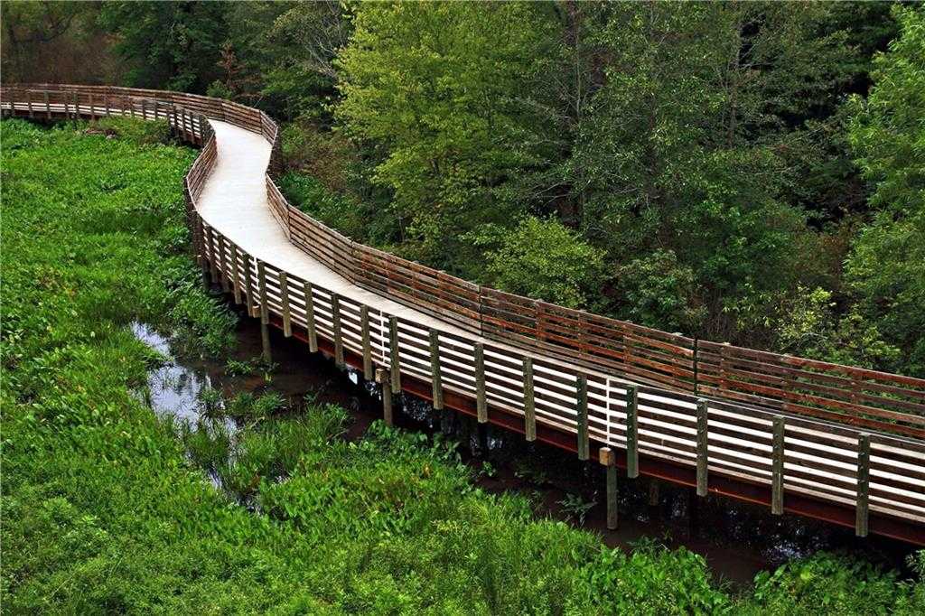 Curving wooden boardwalk over lush green wetlands and trees in Riverwood community, Dallas, Georgia