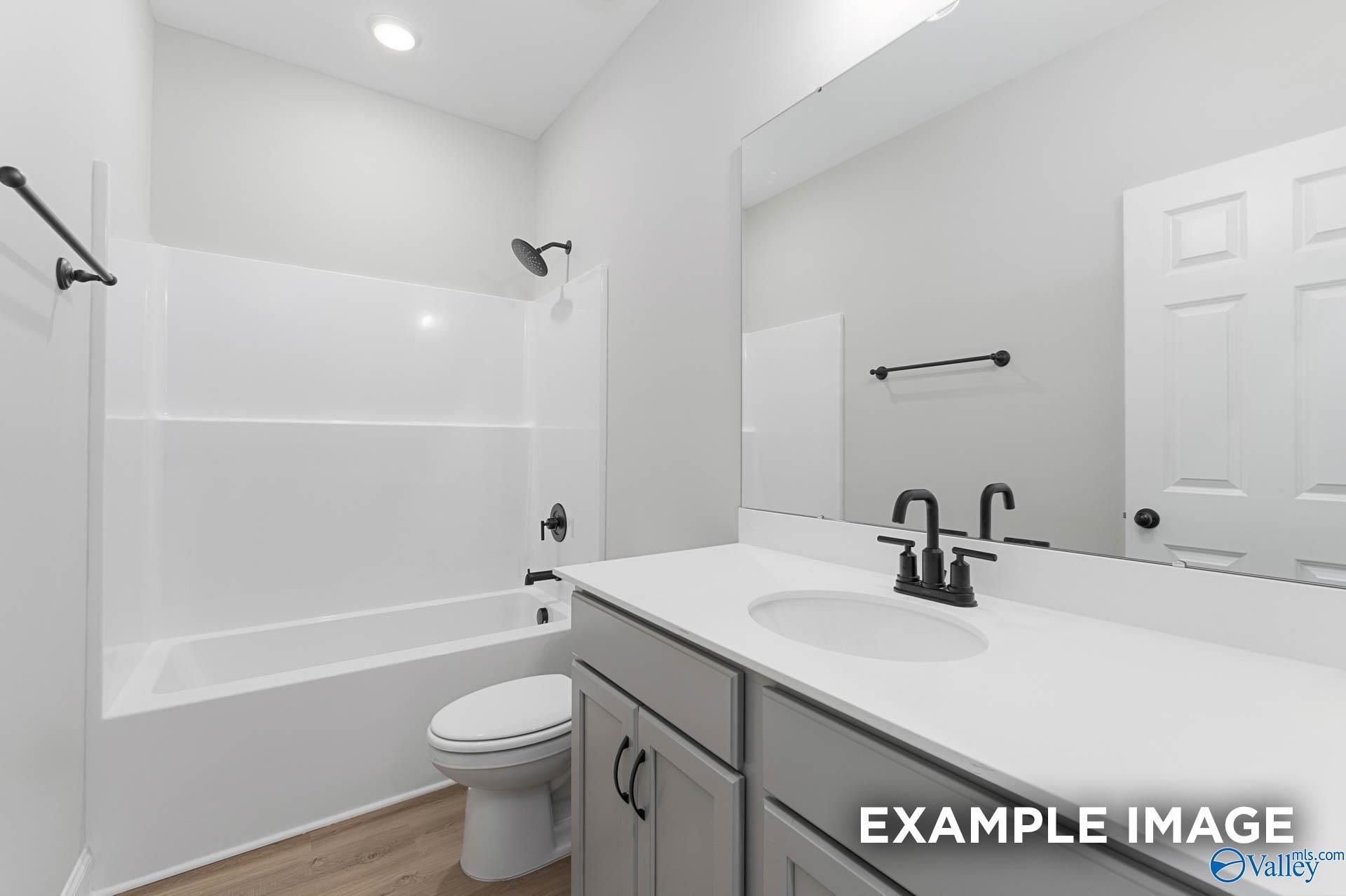 Modern bathroom with white tub-shower combo, single vanity, black fixtures in Davidson Homes The Daphne D, Meridianville, AL