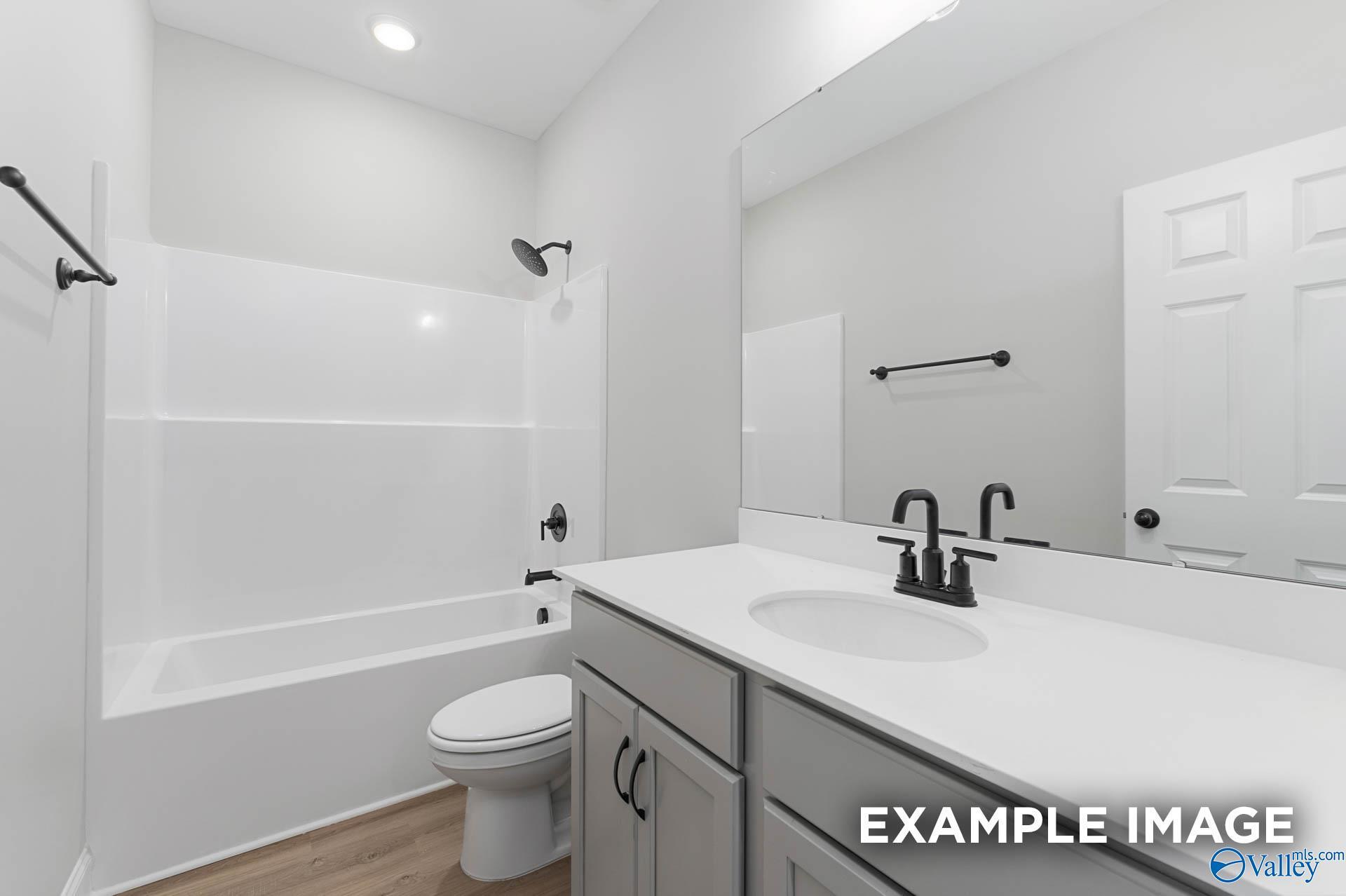 Modern bathroom with white tub-shower combo, single vanity, black fixtures in Davidson Homes The Daphne D, Meridianville, AL