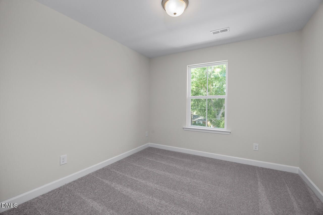 Bright, carpeted bedroom with neutral walls in The Mitchell floor plan by Davidson Homes in Camden Park, Knightdale, NC.