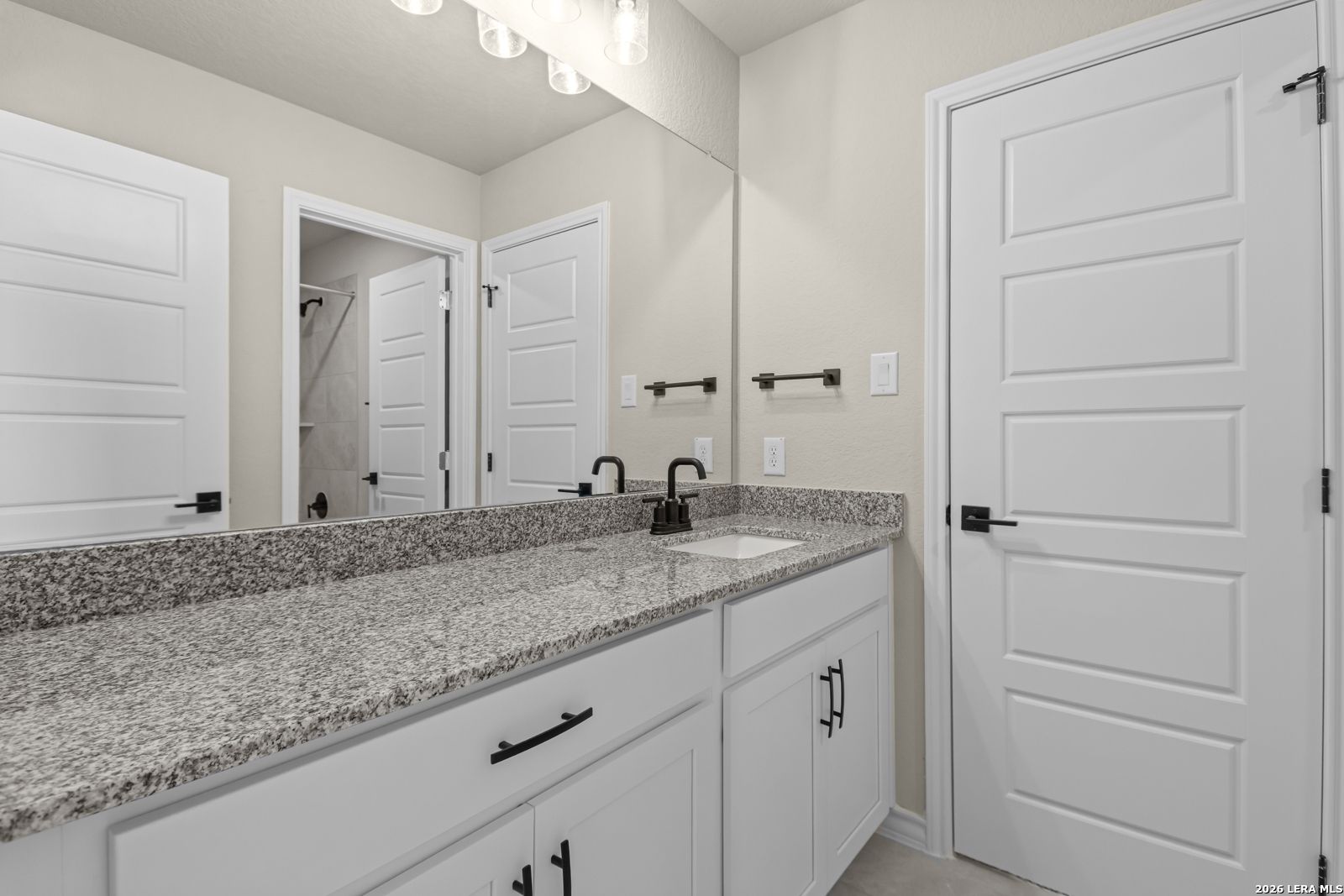 Modern bathroom vanity with granite countertop and black hardware in The Danbury H model at The Reserve at Potranco Oaks.