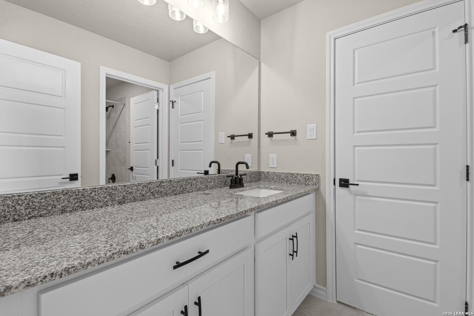 Modern bathroom vanity with granite countertop and black hardware in The Danbury H model at The Reserve at Potranco Oaks.