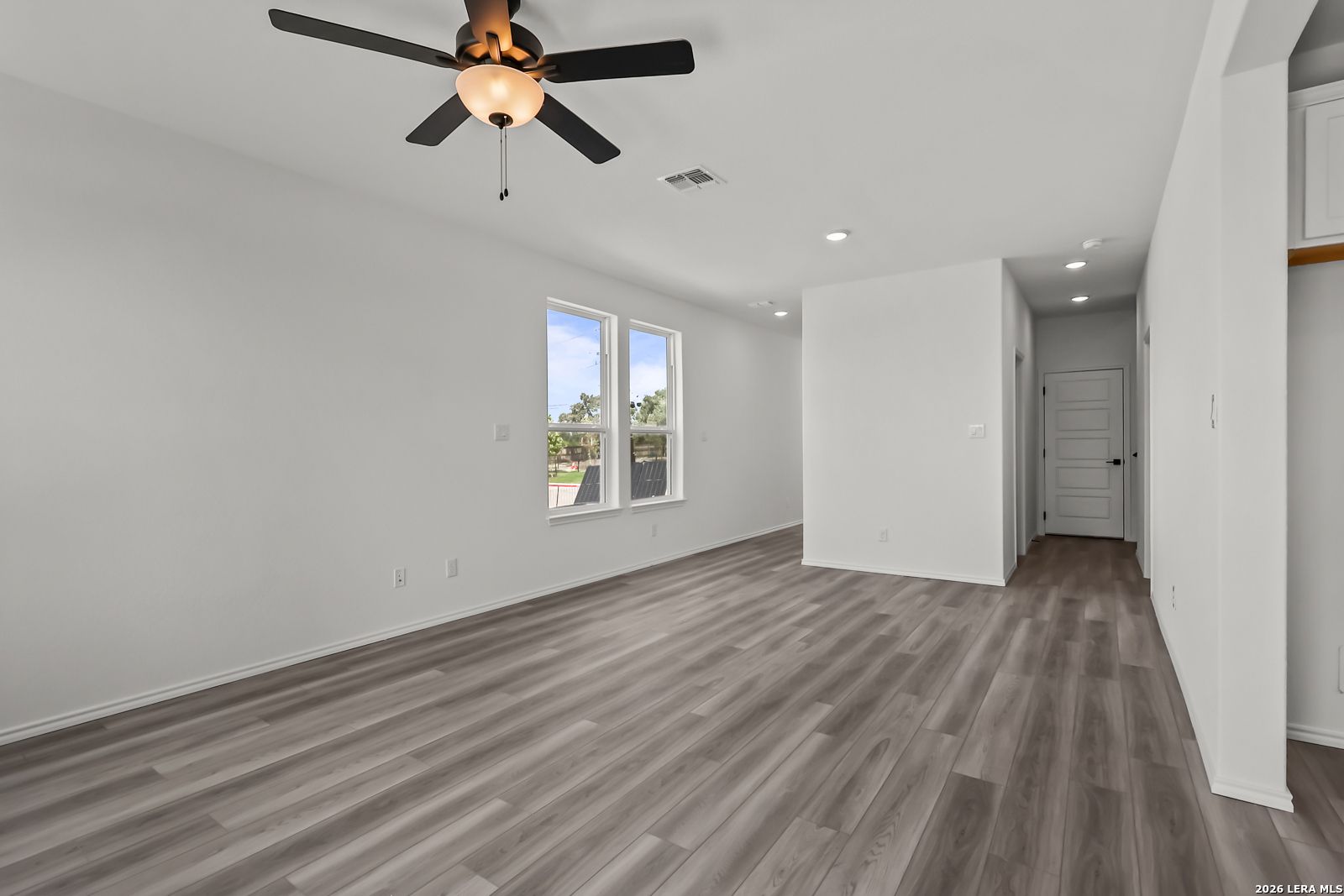 Bright open living area with wood-look flooring in The Florence B floor plan at Meadows at Oak Creek, San Antonio, Texas.
