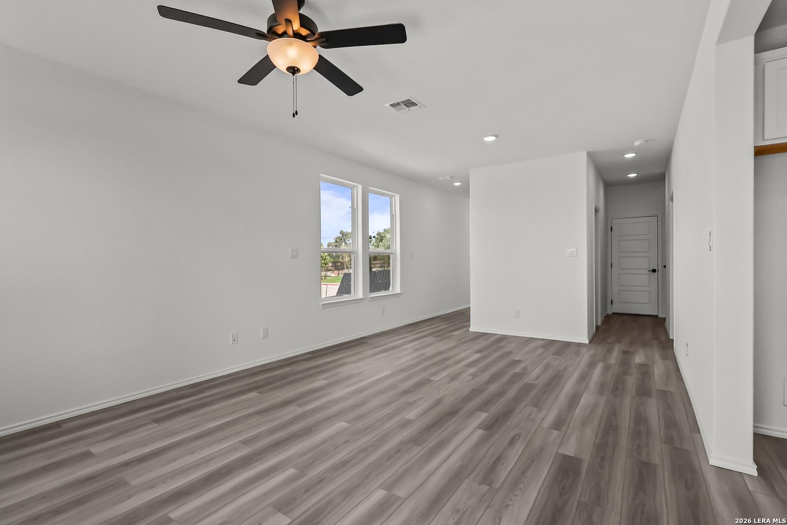 Bright open living area with wood-look flooring in The Florence B floor plan at Meadows at Oak Creek, San Antonio, Texas.