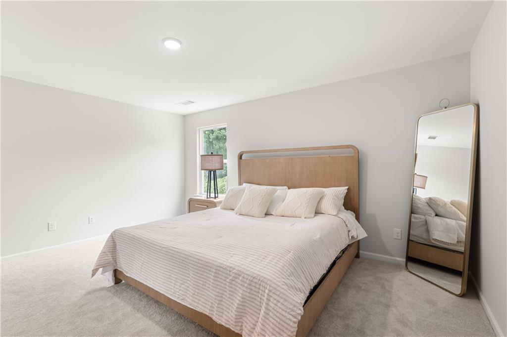 Bright bedroom with a modern bed and floor mirror in The Sinclair B floor plan at Cedar Farms, Winder, Georgia.