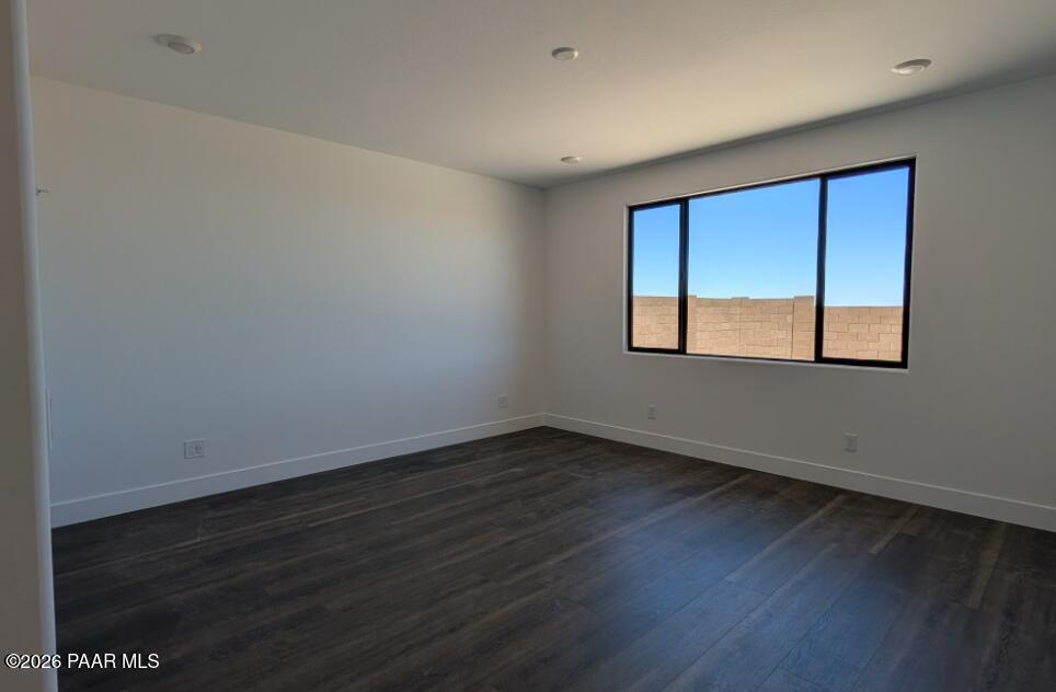 Bright, spacious bedroom with dark wood flooring in The Durango II G floor plan at South Ranch, Prescott, Arizona.