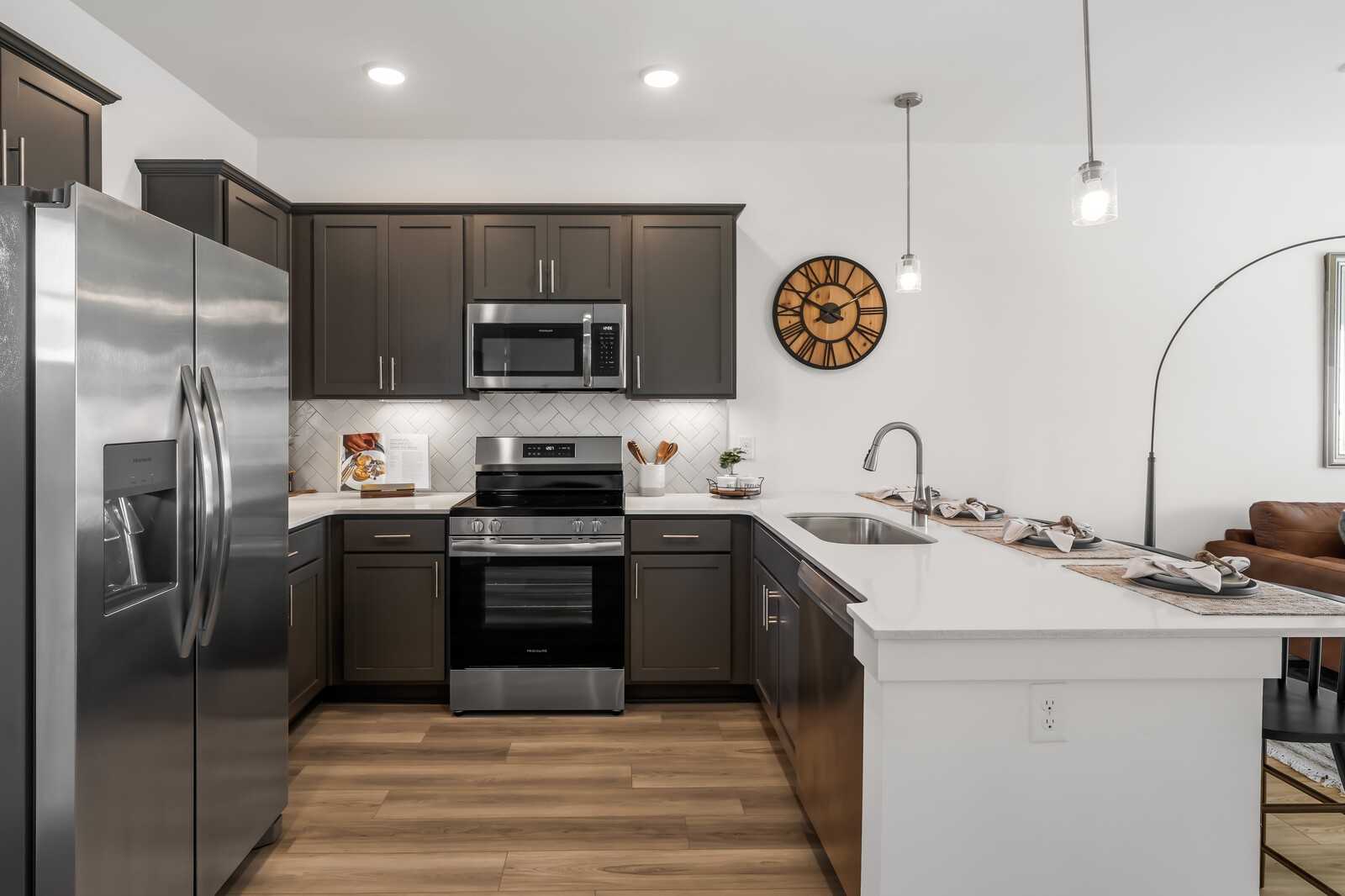 Modern kitchen with dark shaker cabinets, stainless appliances, quartz island in Davidson Homes Cumberland B, Gallatin TN
