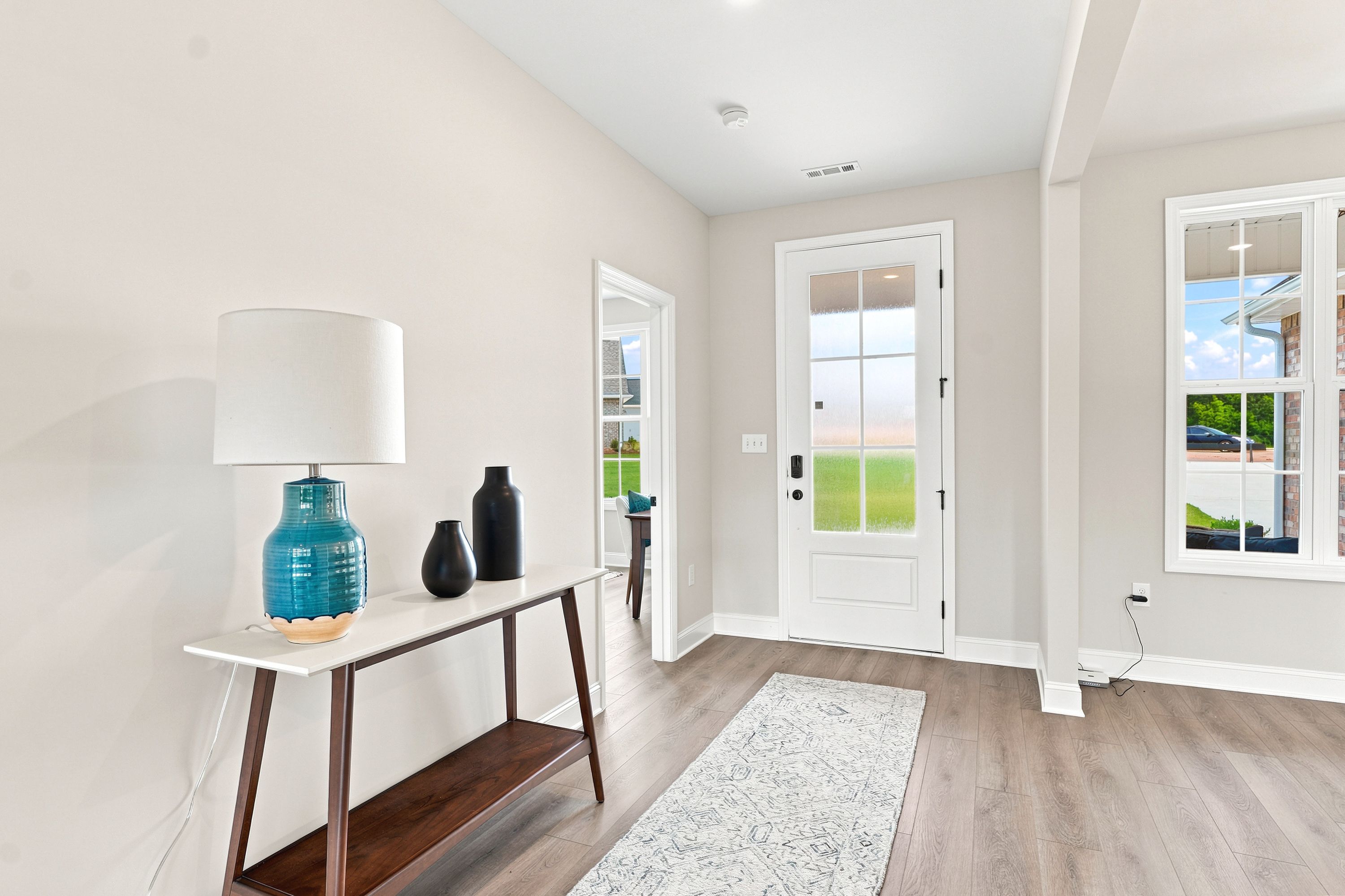 Bright entryway at Riverton Preserve in Huntsville, AL featuring a modern console table, wood flooring, and glass front door.