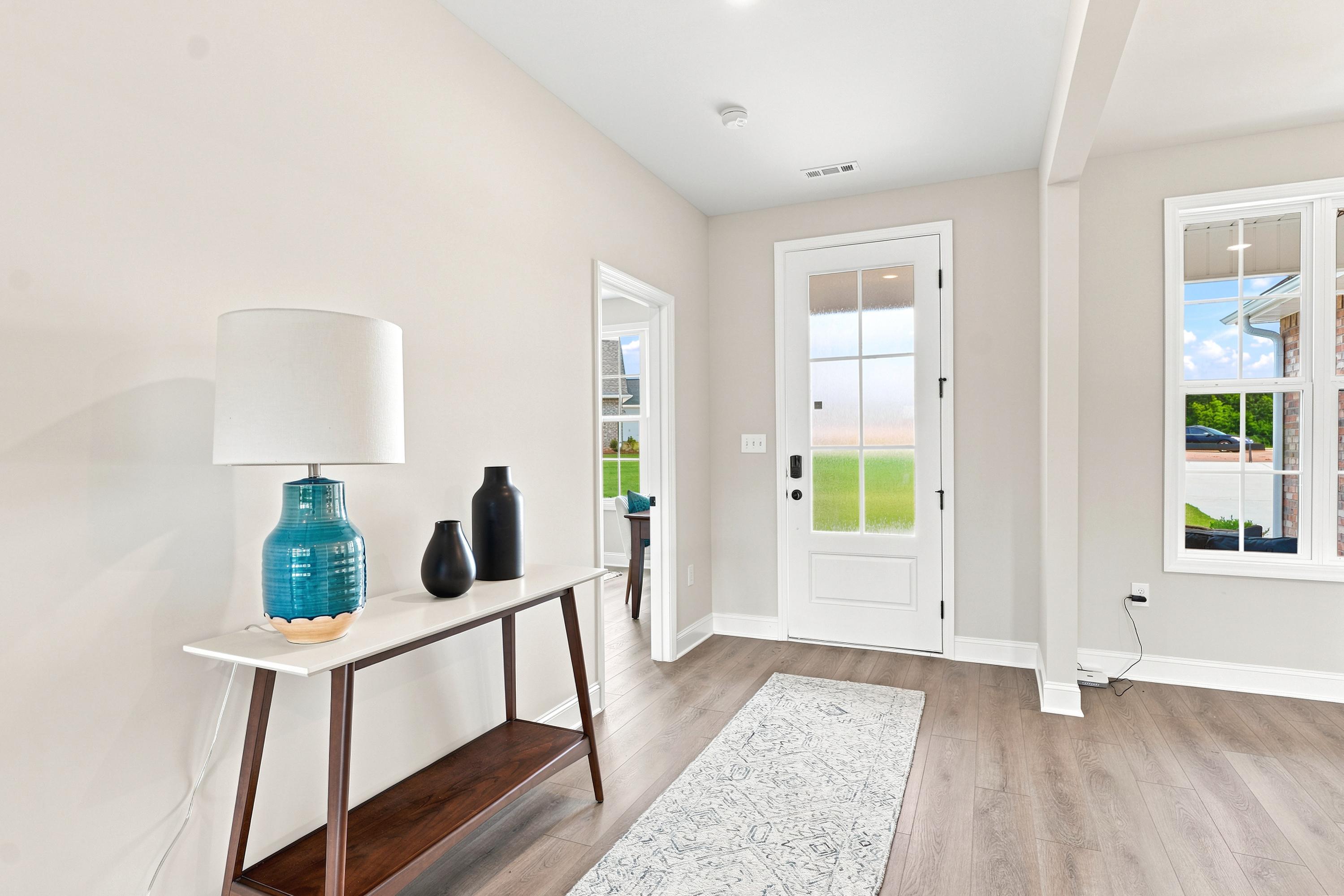 Bright entryway at Riverton Preserve in Huntsville, AL featuring a modern console table, wood flooring, and glass front door.