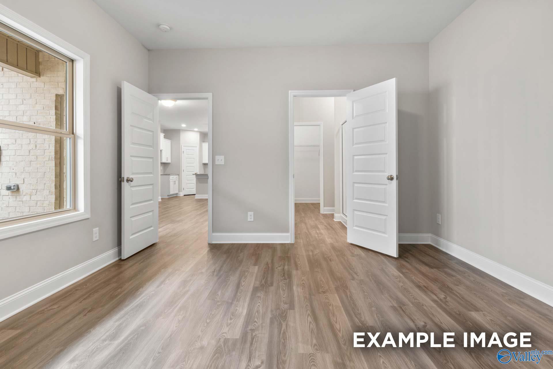 Spacious master suite with hardwood floors, open doors to laundry and bath in Davidson Homes The Camilla C, Hartselle, Alabama