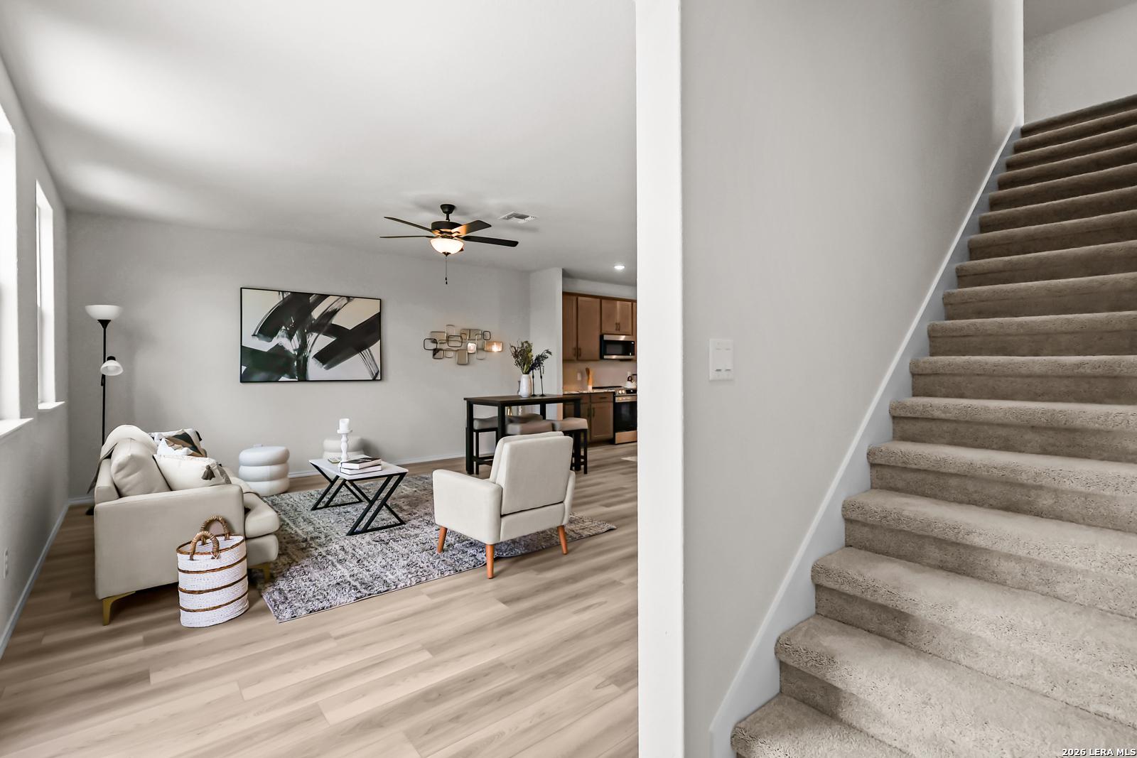 Open-concept living room and dining area with carpeted staircase in The Douglas C floor plan at Hannah Heights, Seguin.