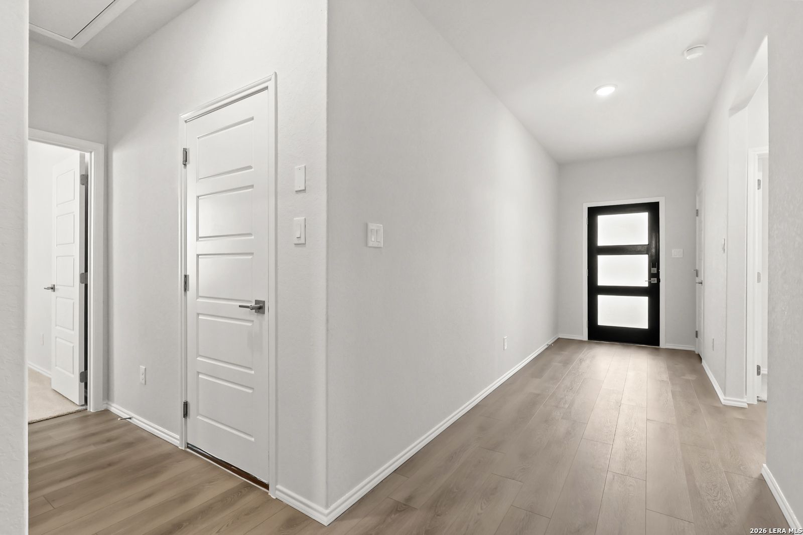 Bright entry hallway with wood-look flooring and black front door in Davidson Homes The Daphne I, Bricewood, San Antonio, Texas
