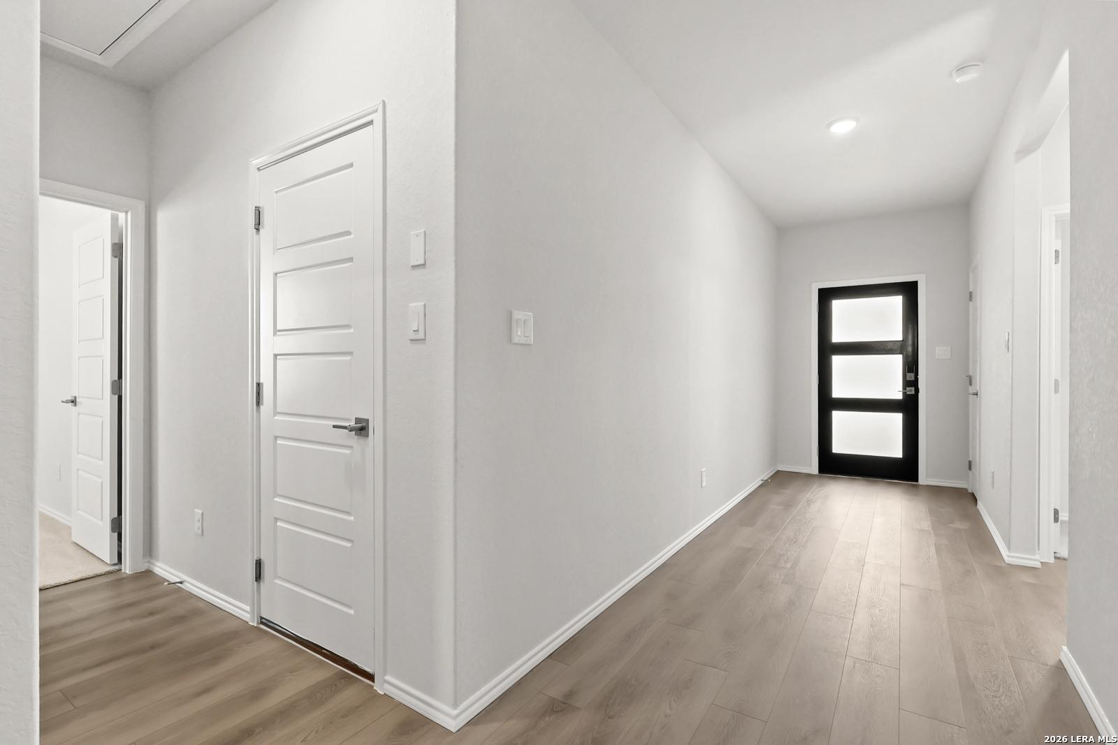 Bright entry hallway with wood-look flooring and black front door in Davidson Homes The Daphne I, Bricewood, San Antonio, Texas