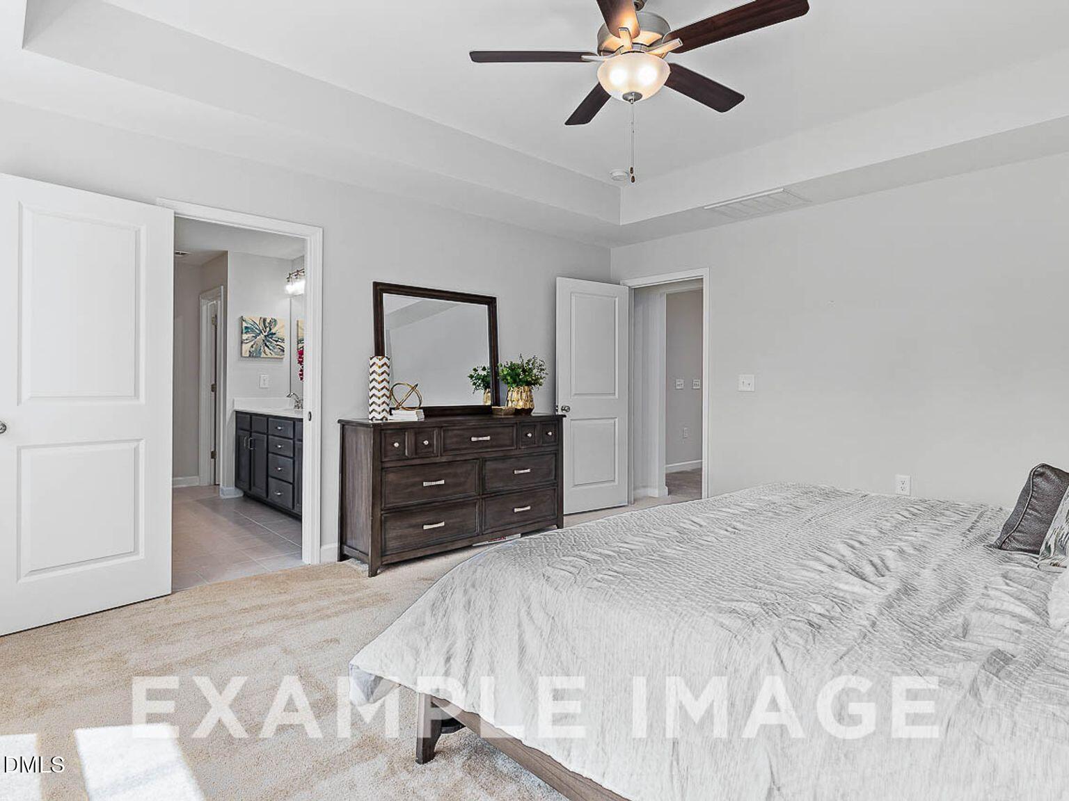 Elegant master bedroom with king bed, dark wood dresser, mirror, ceiling fan, and en-suite bath in Davidson Homes The Chestnut B, Lillington, NC
