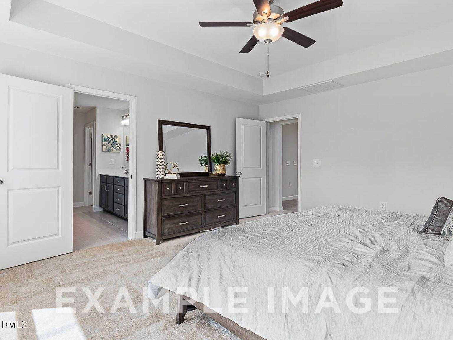 Elegant master bedroom with king bed, wooden dresser mirror, ceiling fan, and en-suite bath in Davidson Homes The Chestnut B, Lillington, NC