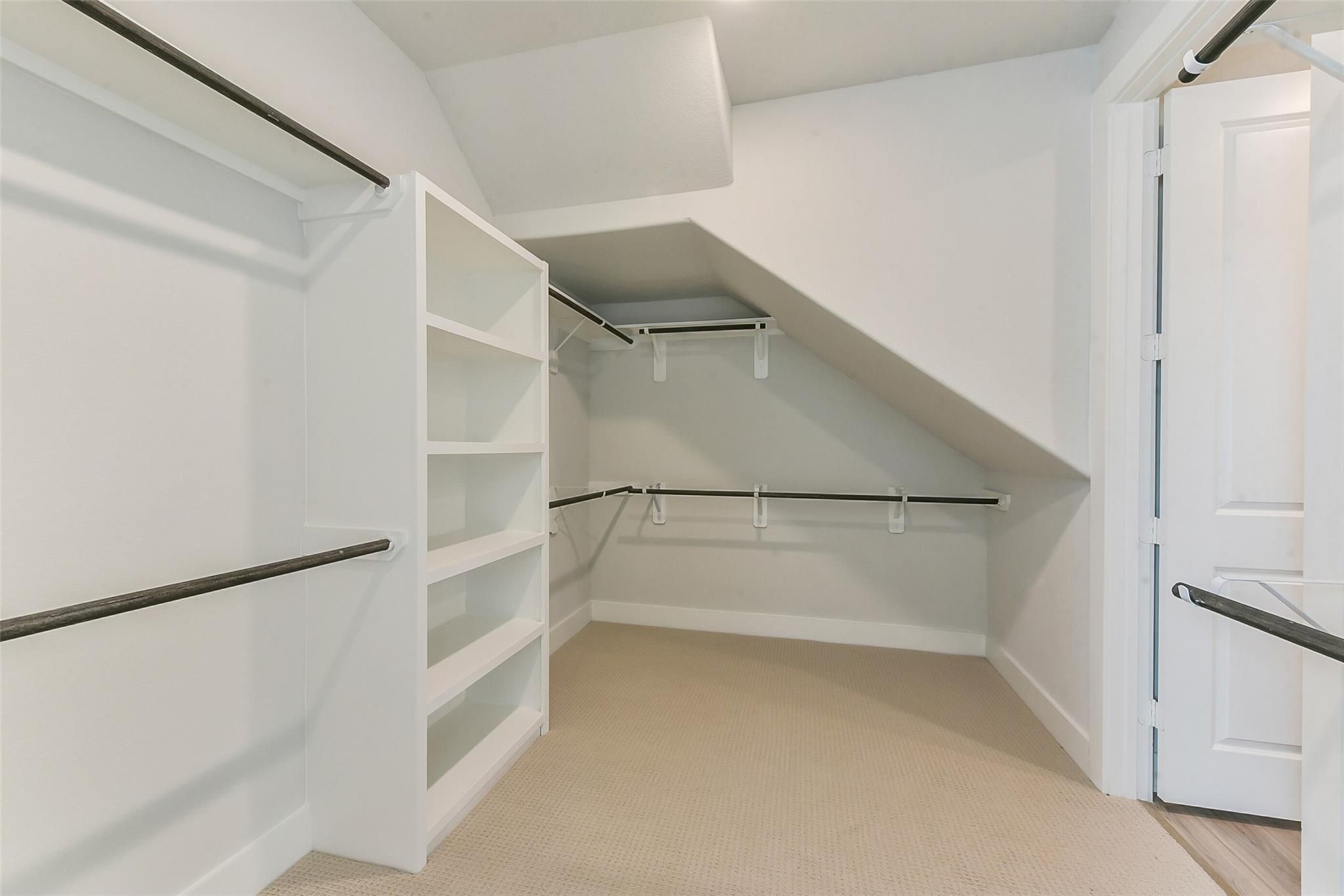 Spacious walk-in closet with white shelves and hanging rods in Davidson Homes The Edward A, Lago Mar, Texas City, Texas