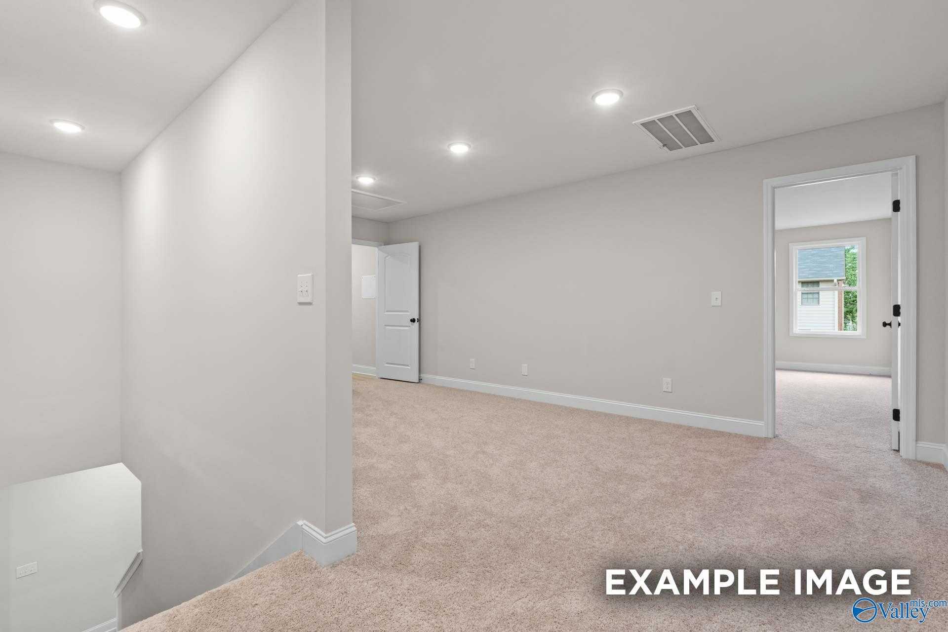 Spacious carpeted bedroom with large window, white doors, and recessed lighting in Davidson Homes The Camden D, Huntsville, Alabama