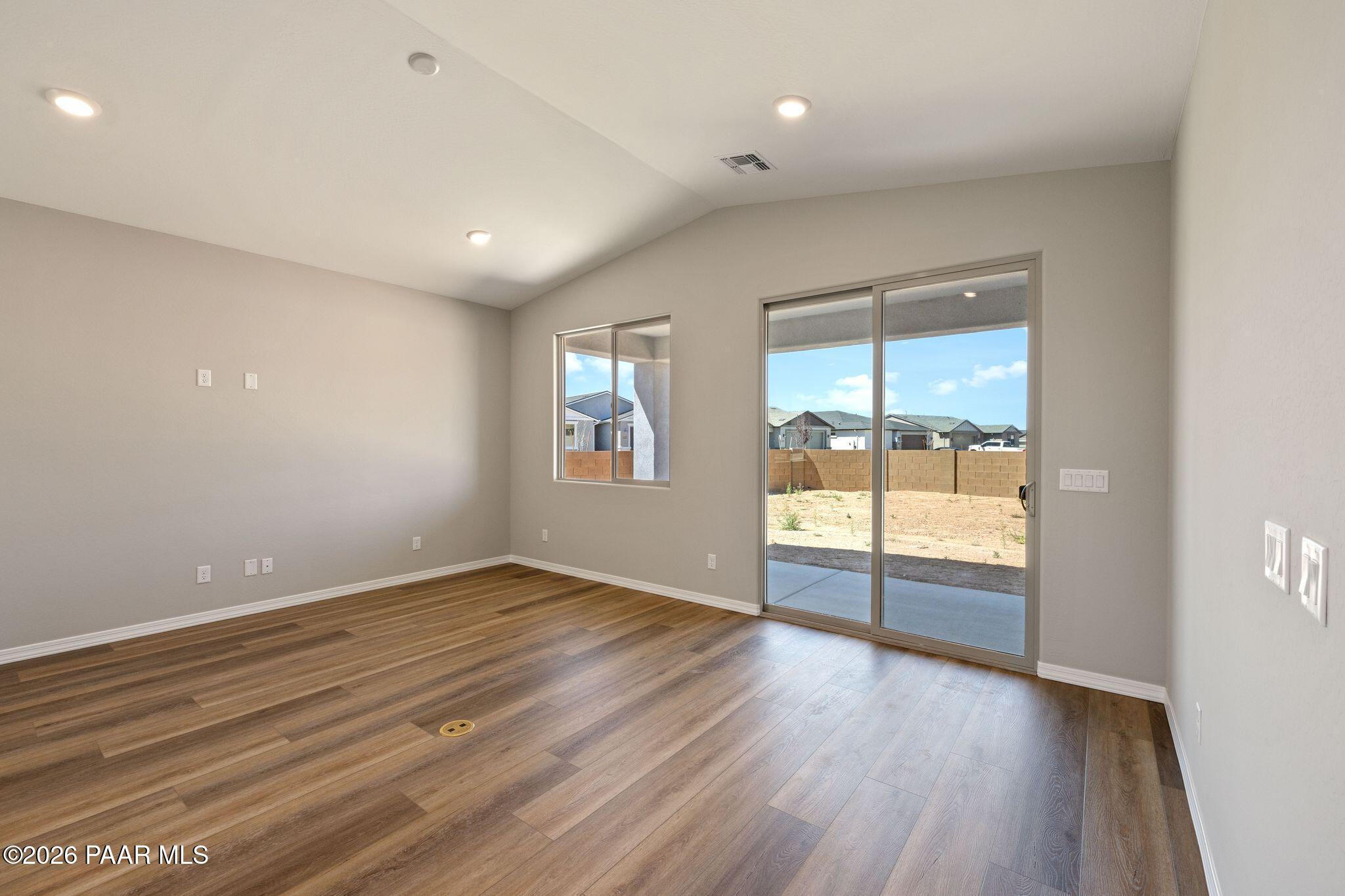 Bright living room with neutral walls, wood-look flooring, and sliding doors to desert backyard in The Frontier A, Prescott Valley, AZ