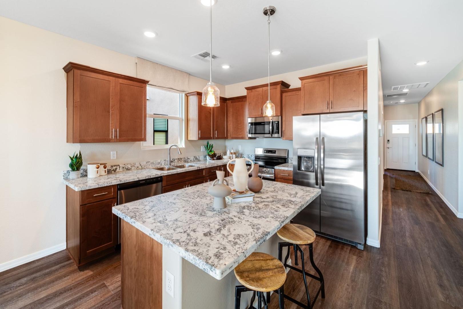 Spacious kitchen in The Savannah B Davidson Homes with warm wood cabinets, granite island, stainless appliances, and hardwood floors