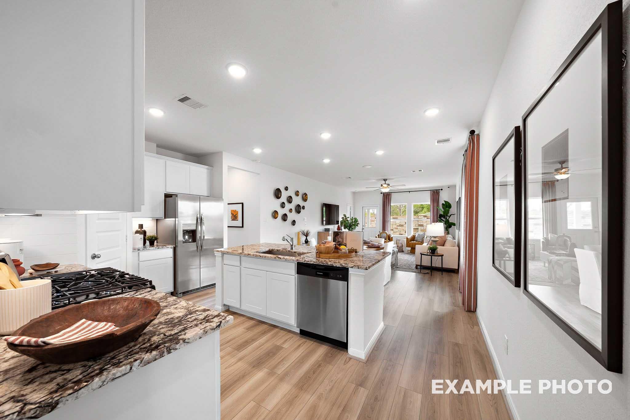 Open-concept kitchen with granite island and stainless appliances in The Sabine E floor plan at Liberty Estates, Cleveland.